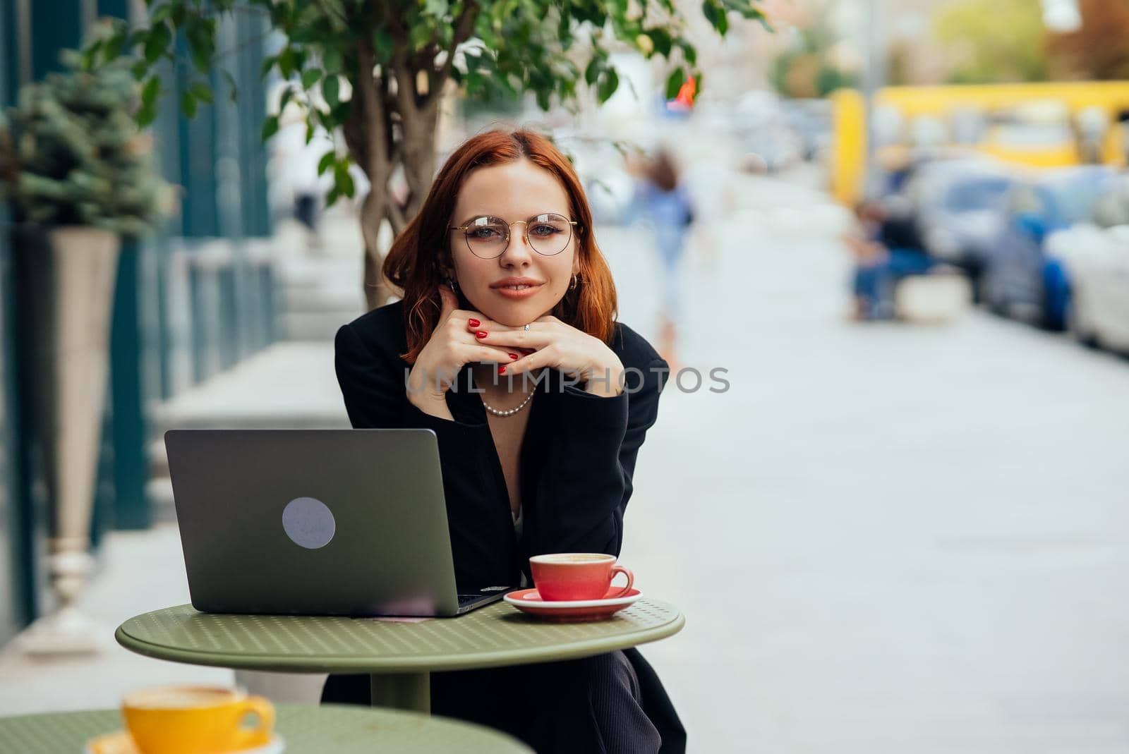Happy young woman in a street cafe looks into the camera