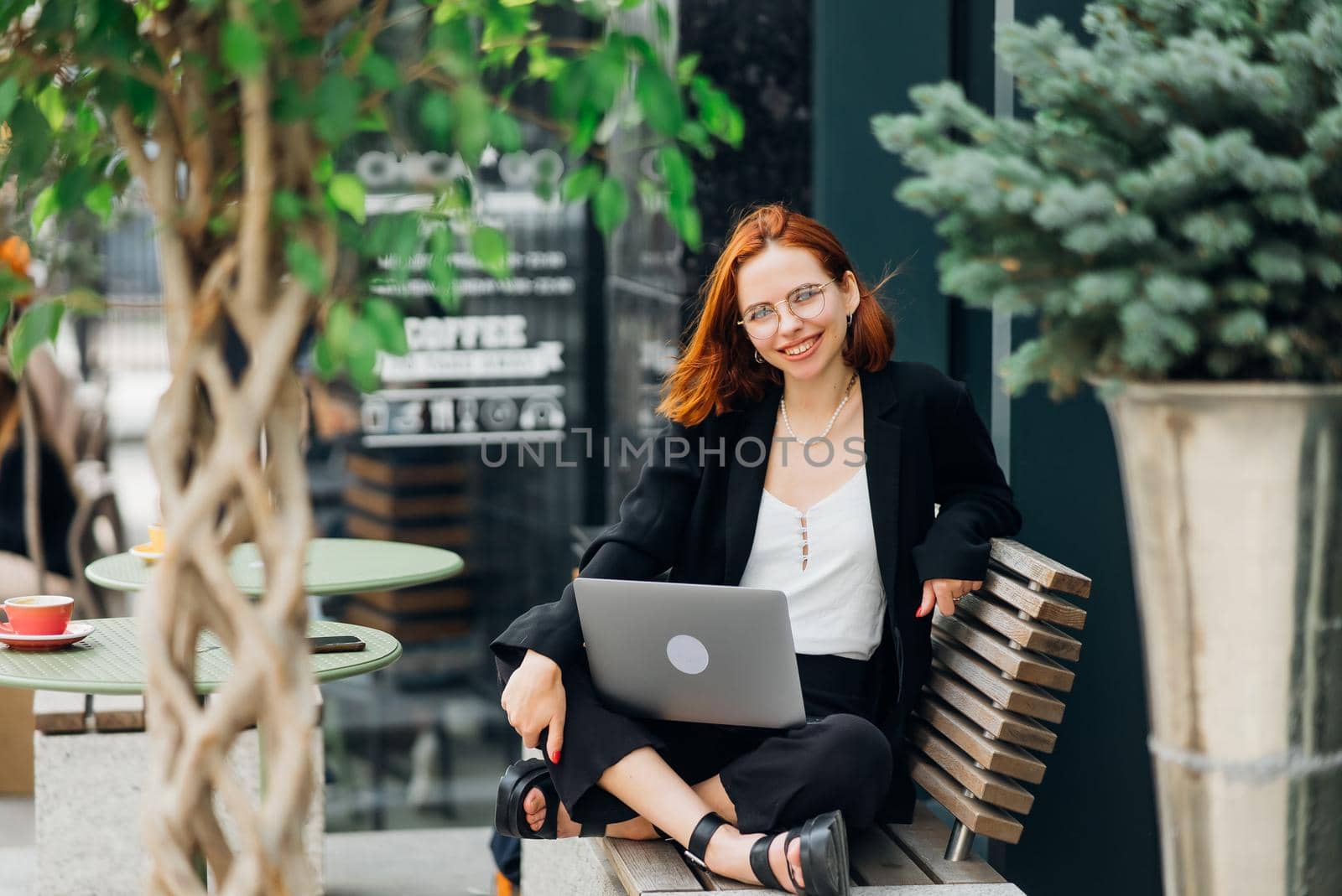 Beautiful redhead woman working on laptop at outdoors cafe