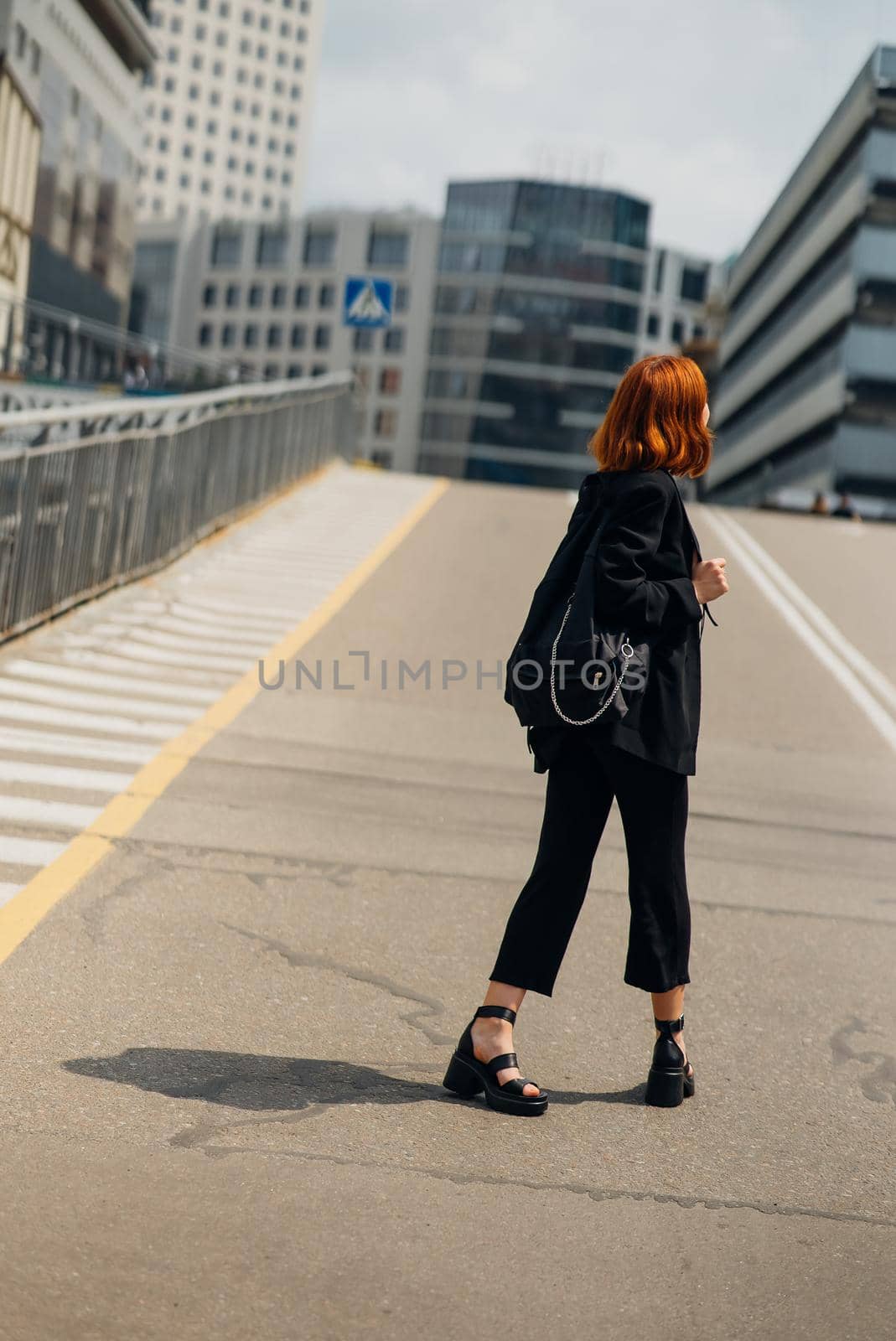 Young beautiful smiling happy woman with backpack poses on a camera while standing on the road