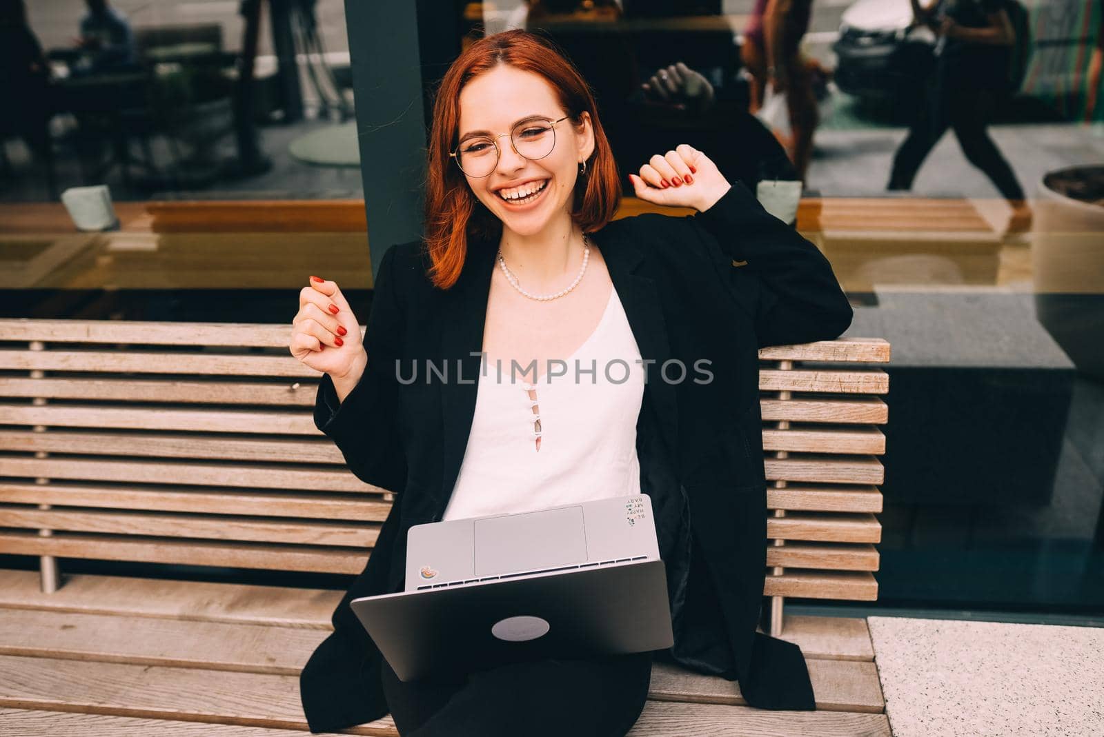 Beautiful redhead woman working on laptop at outdoors cafe