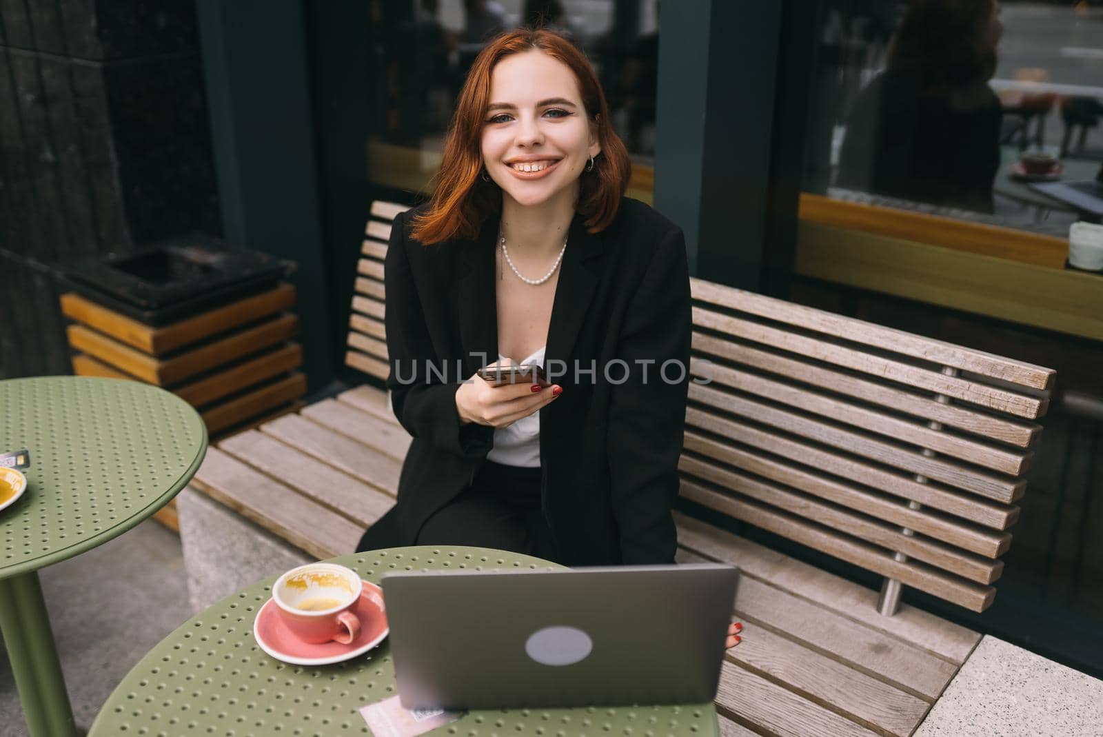 Attractive brunette woman at the street cafe reading a text messageon a phone.