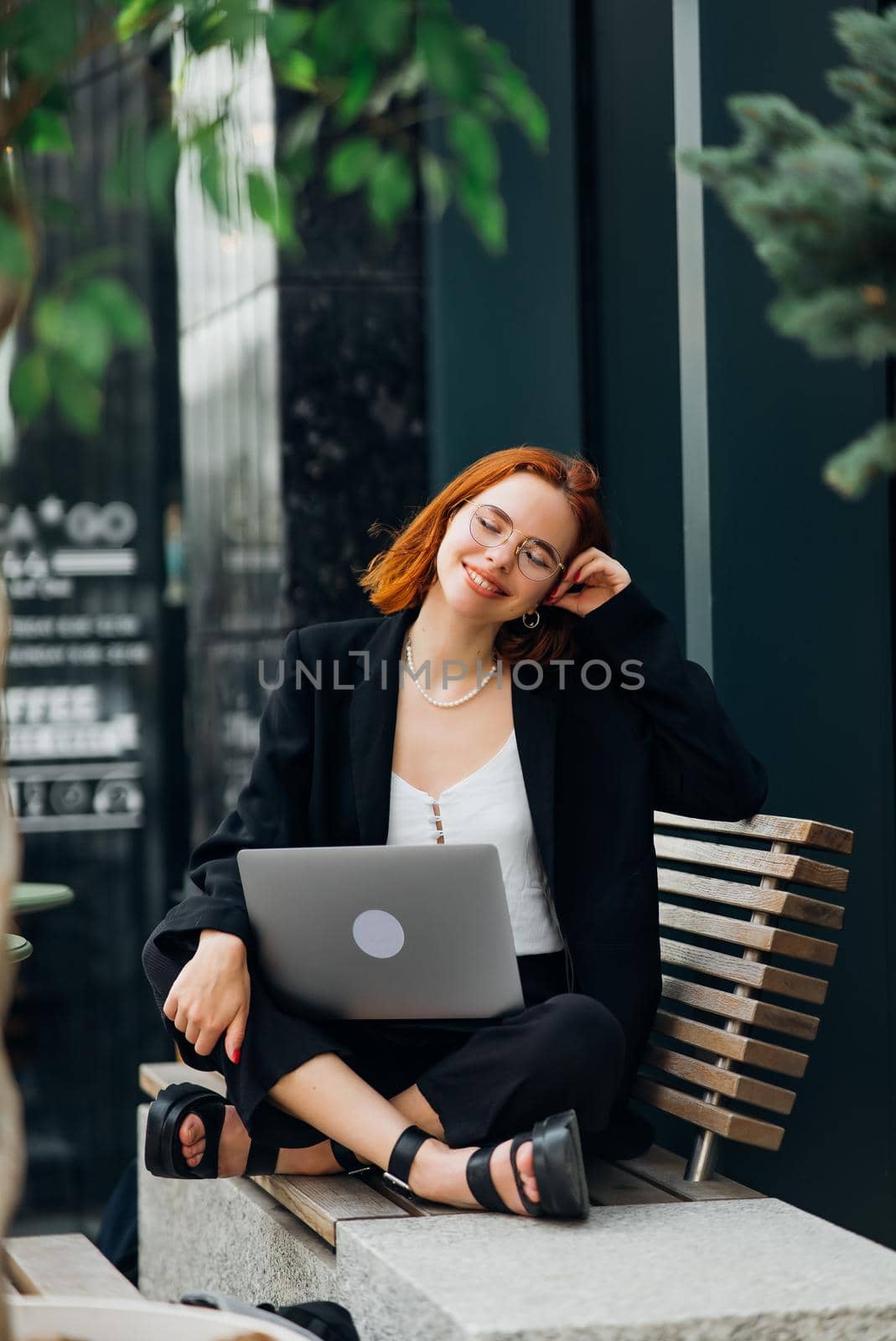 Beautiful redhead woman working on laptop at outdoors cafe