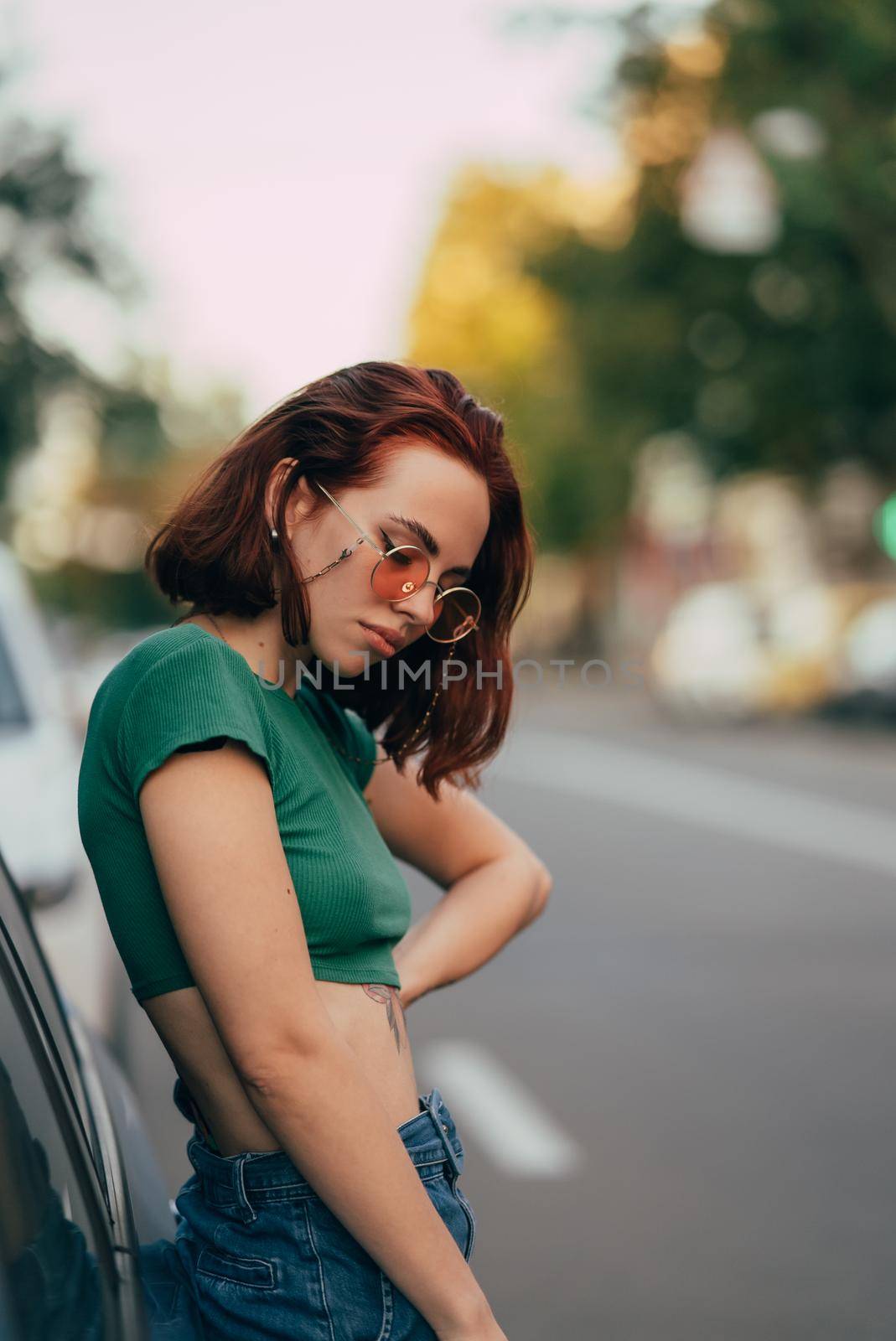 Young woman in glasses posing near car