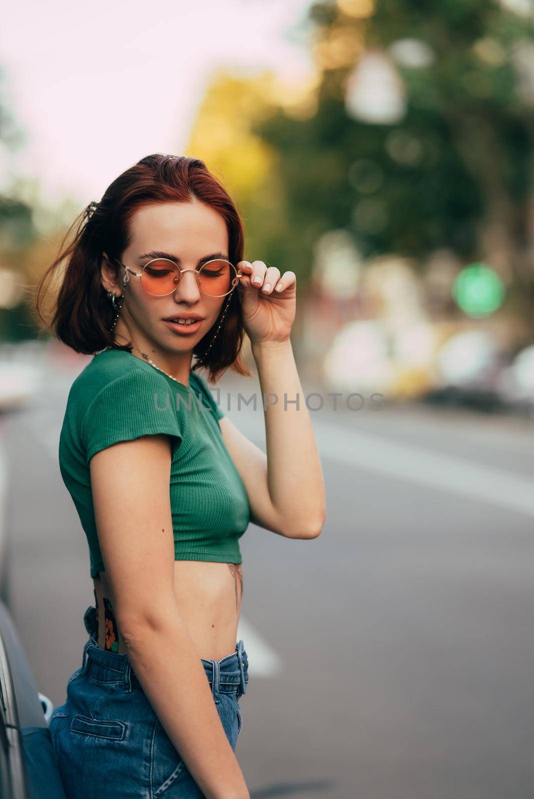 Young woman in glasses posing near car
