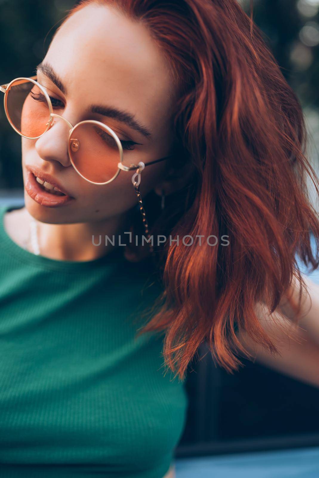 Young woman in glasses posing near car
