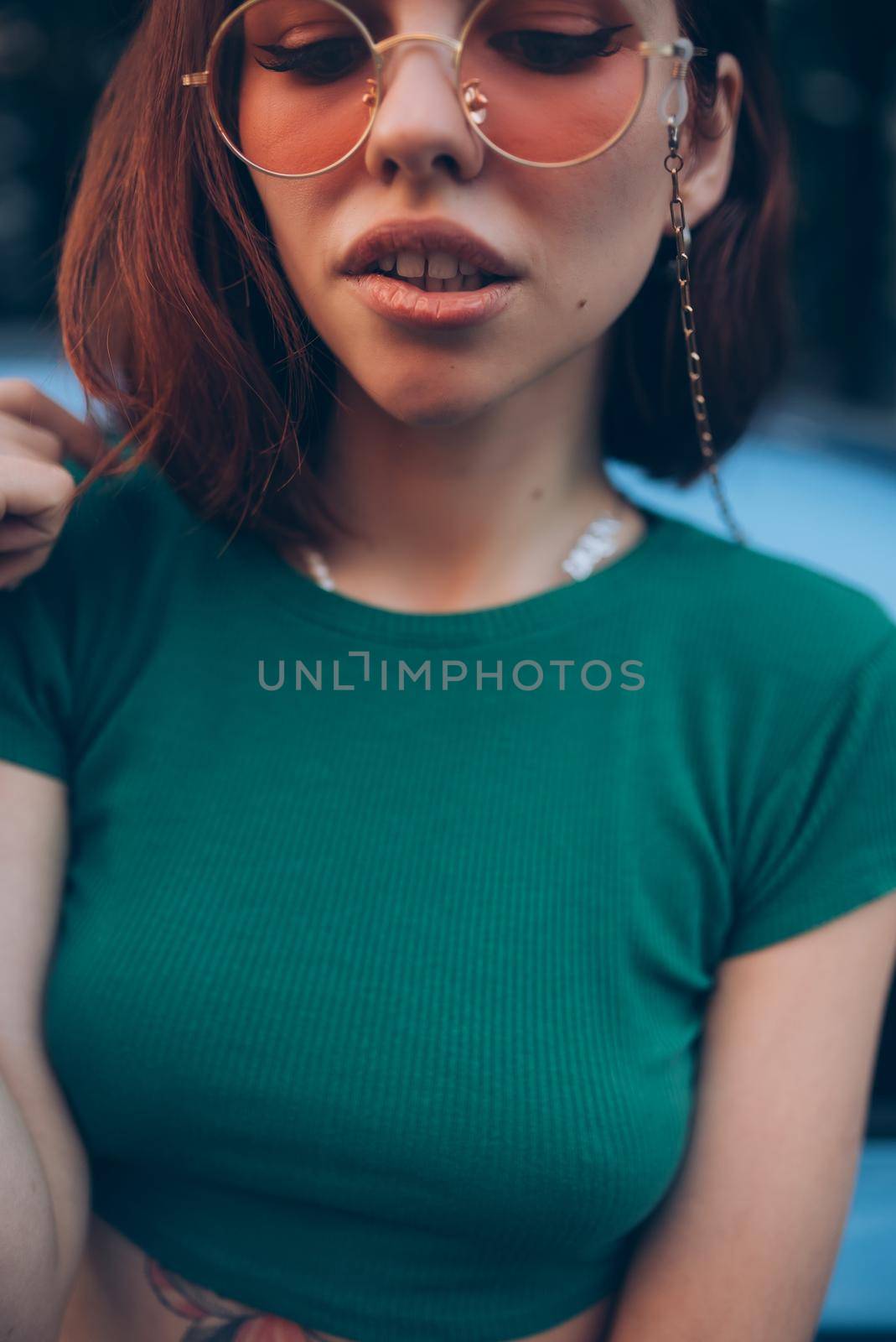 Young woman in glasses posing near car