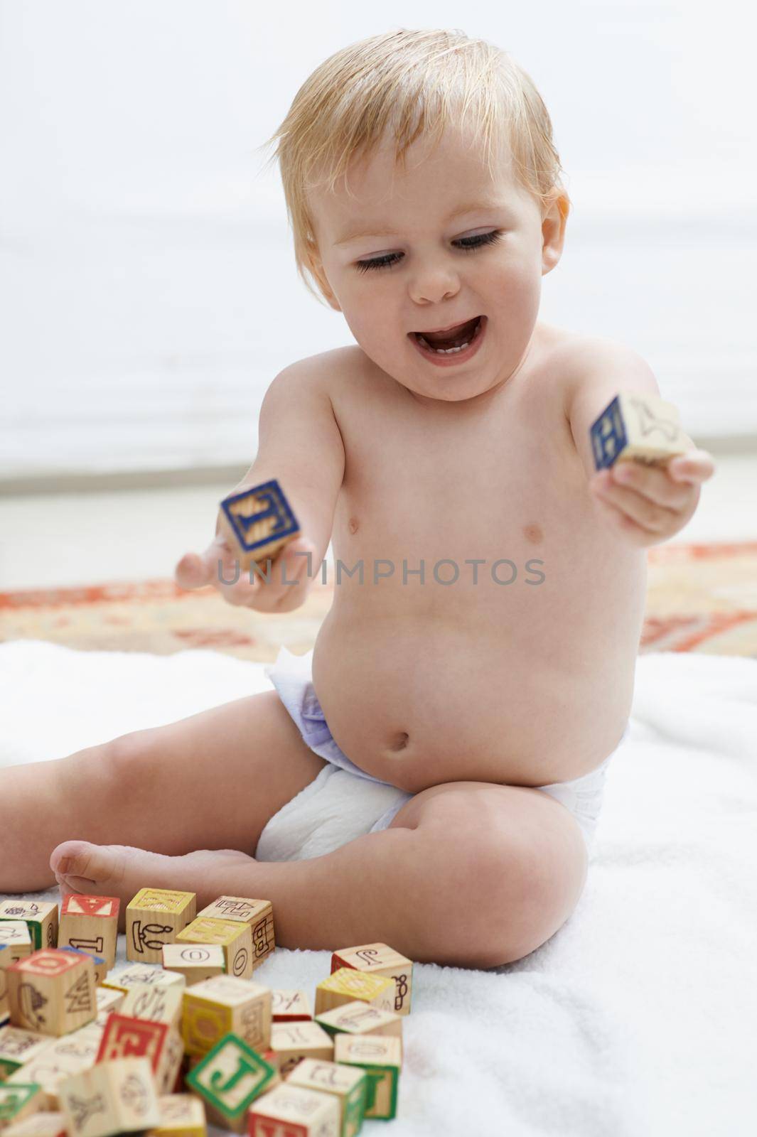 Showing interest in educational games. A baby playing with his building blocks looking content
