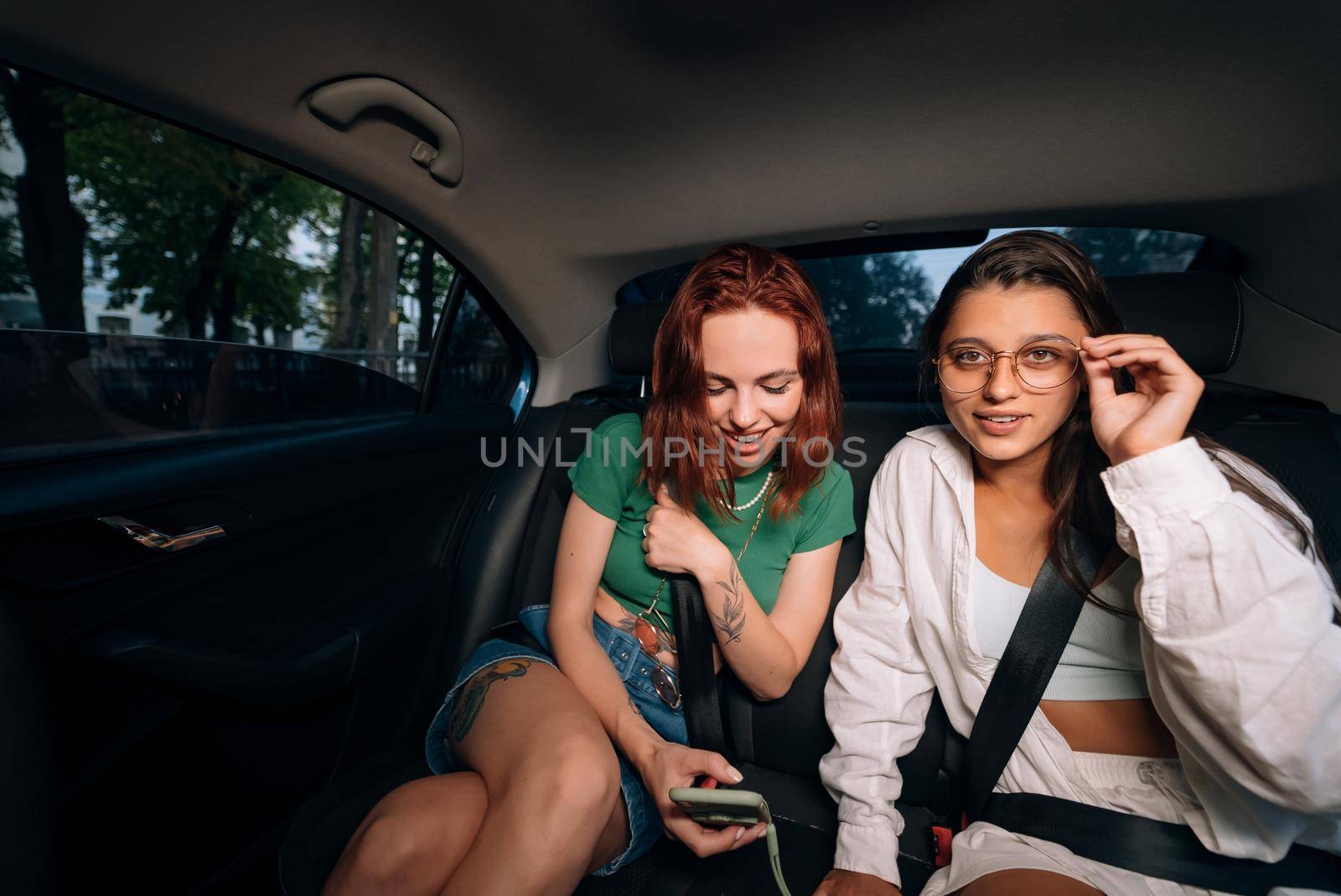 Friends together in the back seat of a taxi by teksomolika