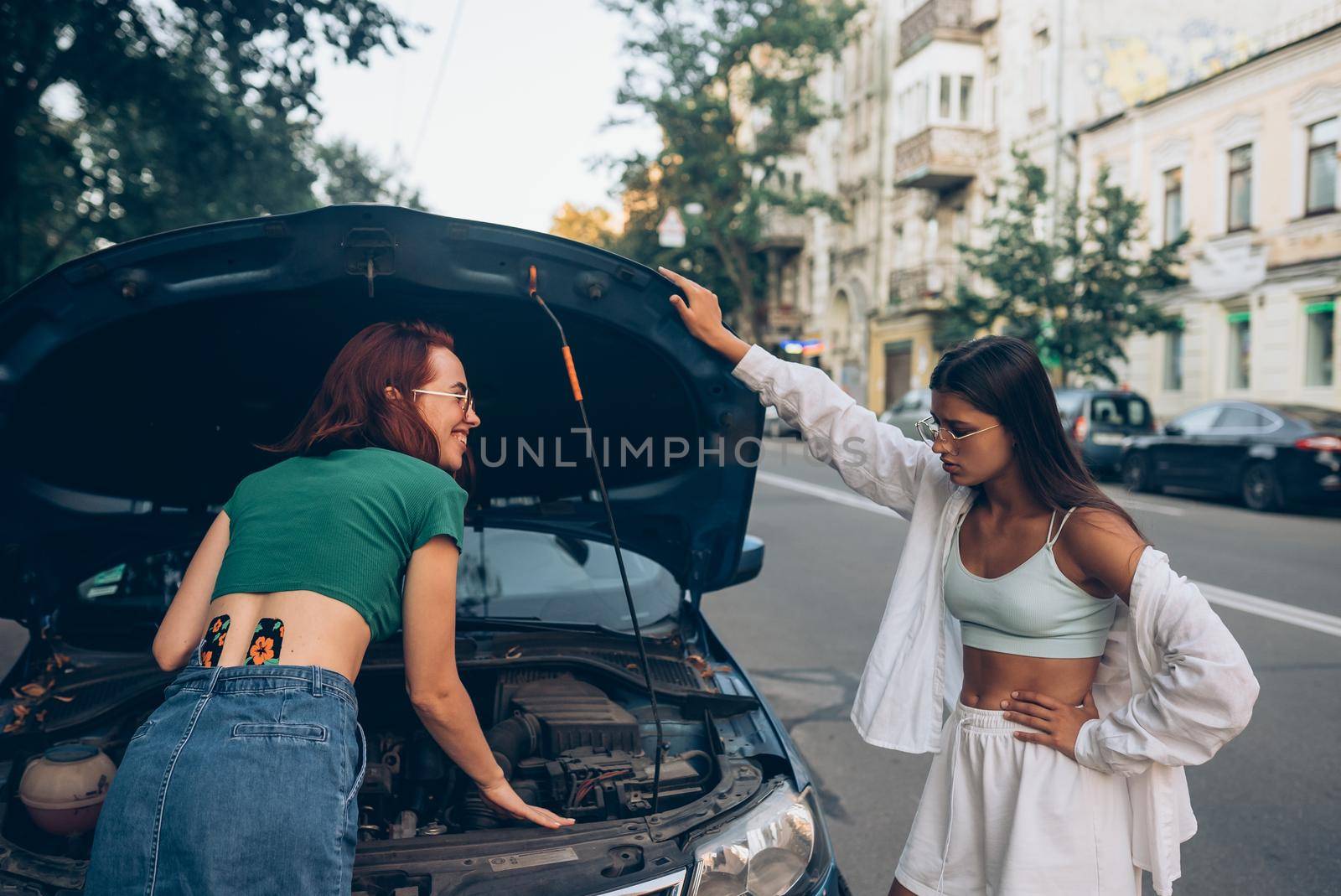 Two women with broken car on the road. Open hood by teksomolika
