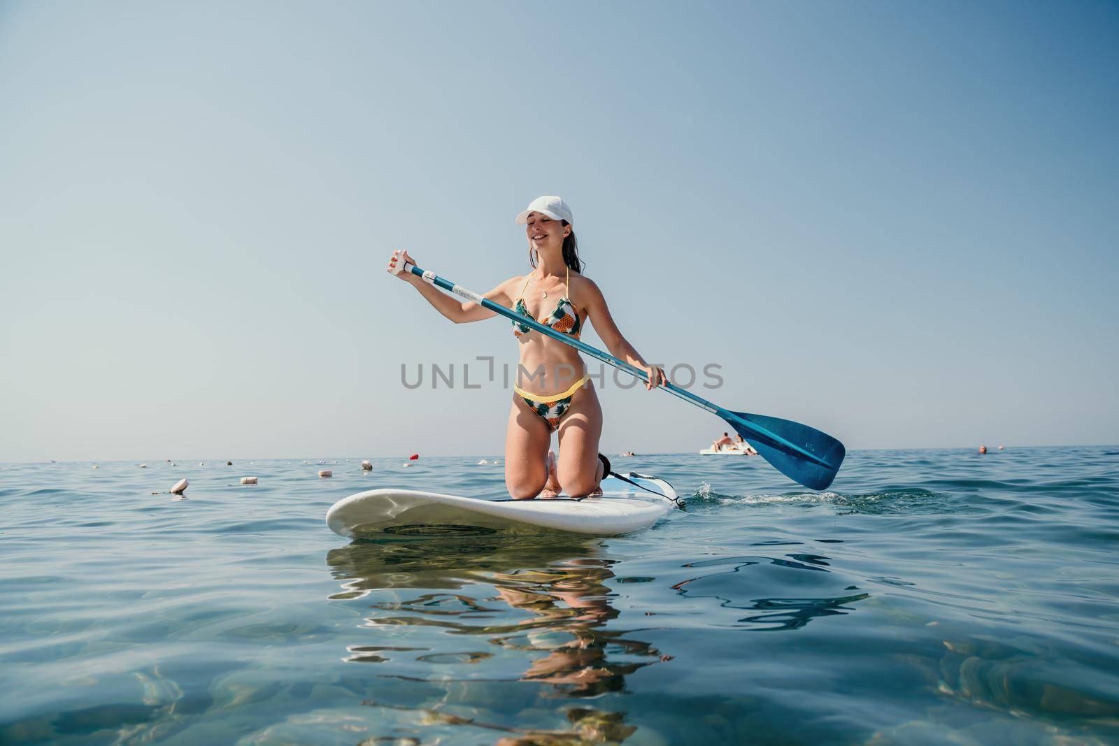 young woman in swimsuits doing yoga on sup board in calm sea, early morning. Balanced pose - concept of healthy life and natural balance between body and mental development