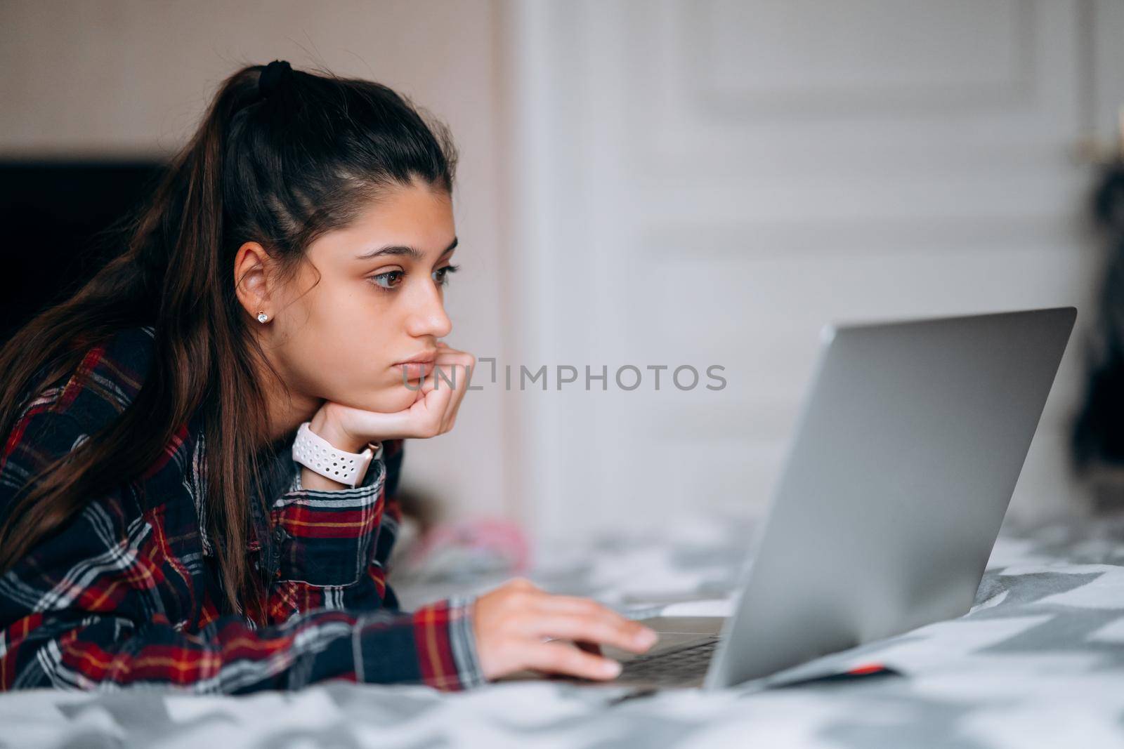 Selective focus of young woman work while with laptop lying on bed