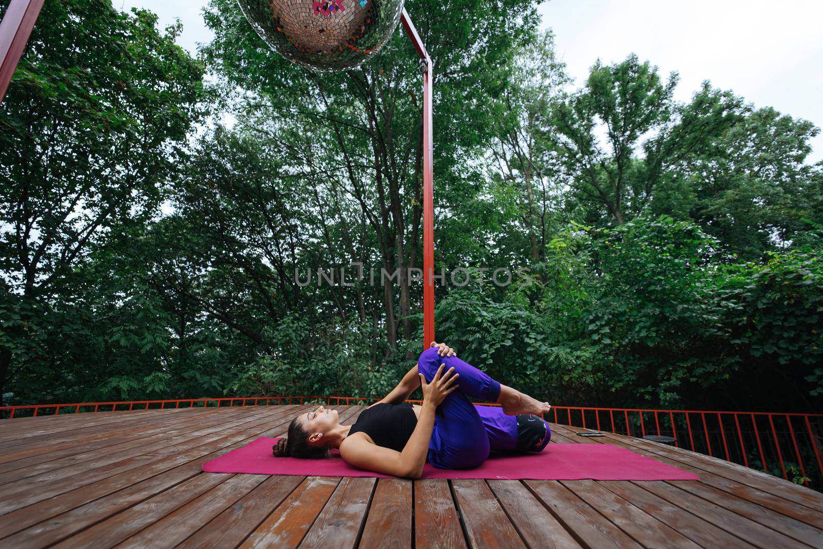 A young woman in doing yoga in the yard on the veranda