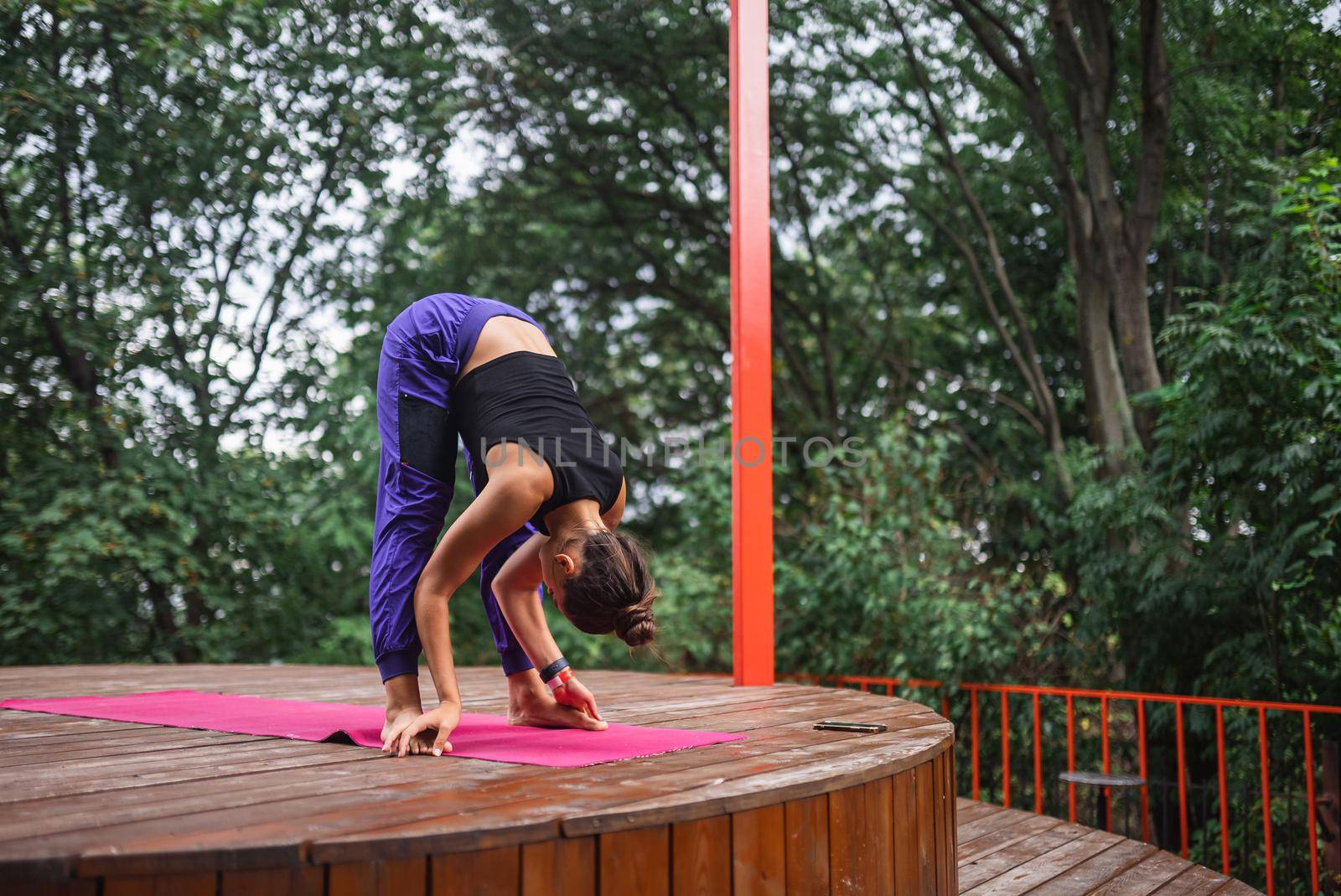 A young woman in doing yoga in the yard on the veranda