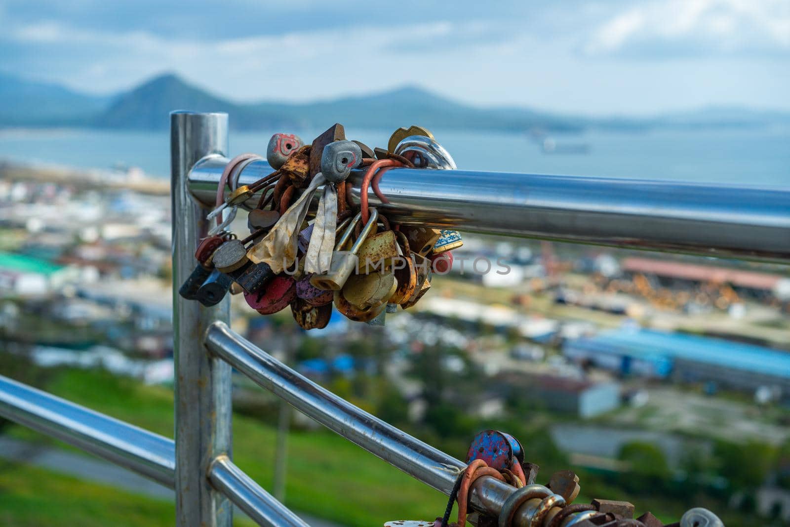 Metal fence with locks on a blurry background of the city by Vvicca