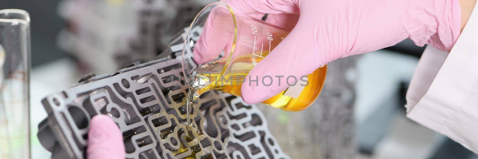Close-up of mechanic man pouring liquid purified oil on automobile part. Lubricating liquid in glass flask, repair car detail. Pit stop, testing concept