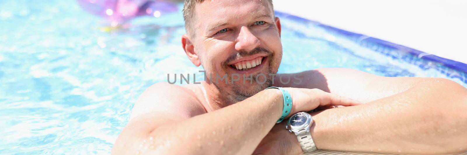Portrait of middle aged man chill in swimming pool on summer holiday. Happy person on hotel territory. Summer, resort, leisure, trip, relaxation concept