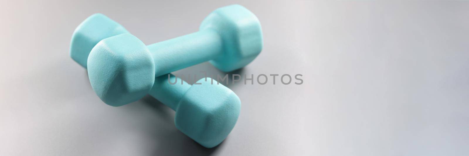 Close-up of pair of blue dumbbells on grey surface, planning weight loss, equipment for sport activity. Sport, health, physical activity, habit concept