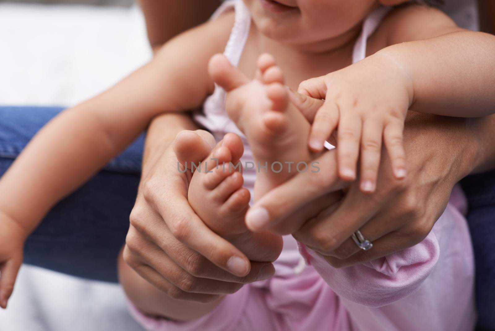 This little piggy went to market...A cropped image of a mother holding her baby girl. by YuriArcurs