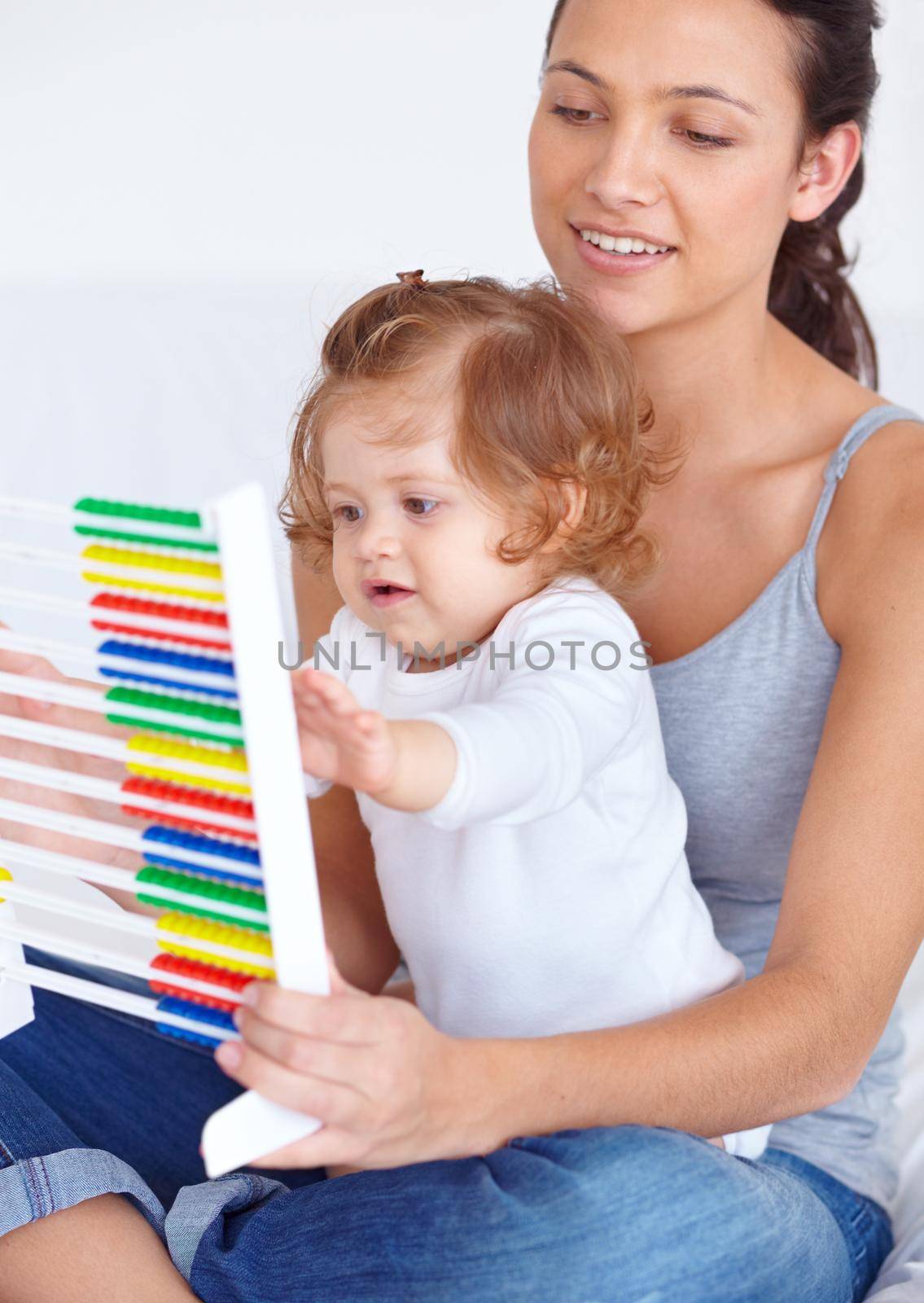 Learning at home. A young mother teaching her baby daughter the basics of mathematics by using an abacus