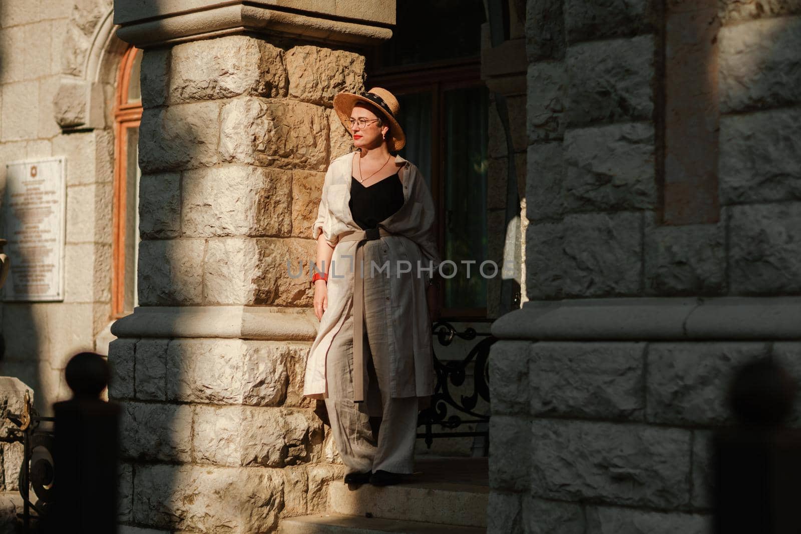 A woman in a hat in a white outfit with a bag walks around the Livadia Palace.