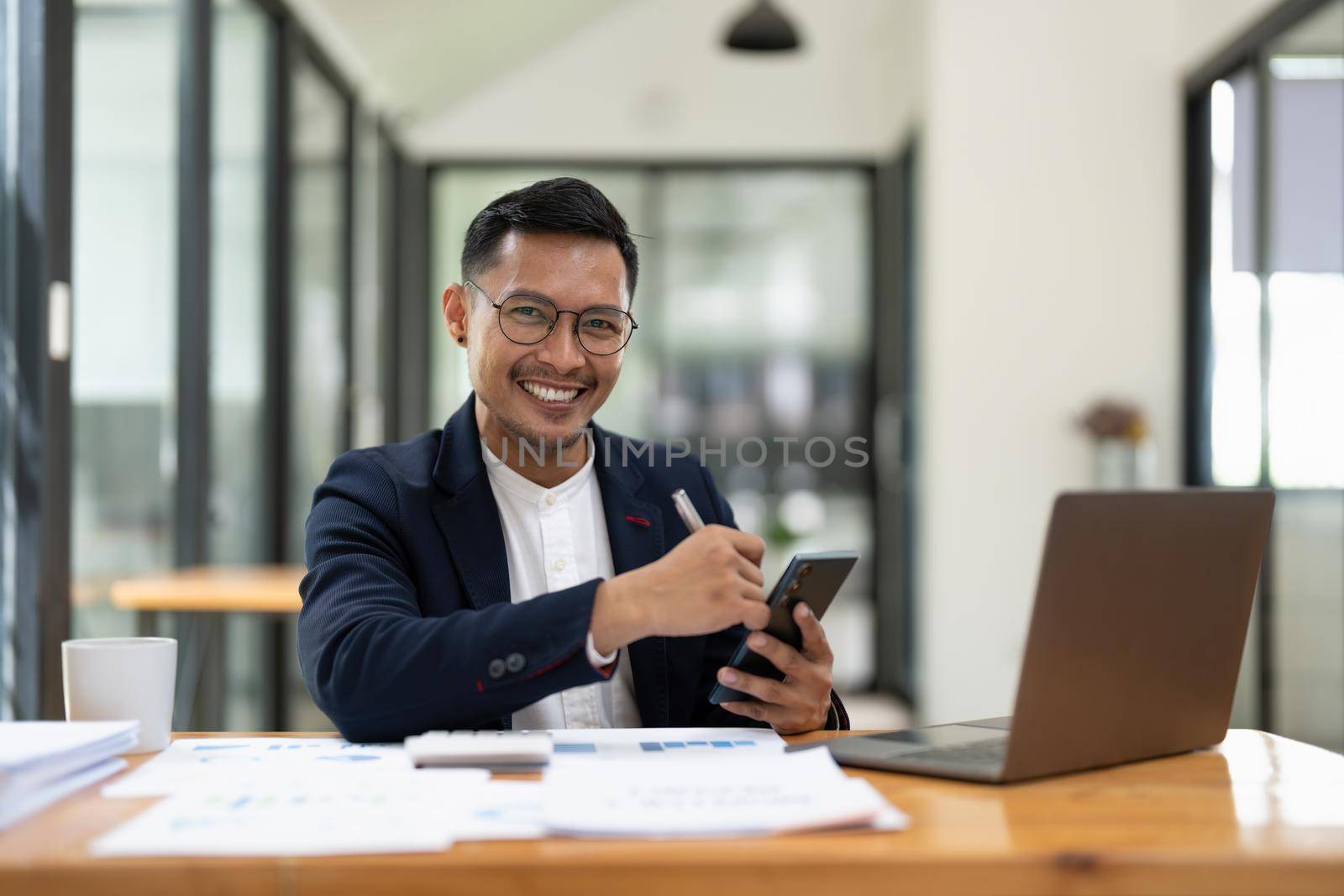 Portrait of a business man using mobile phone. asian business men working with laptop at office