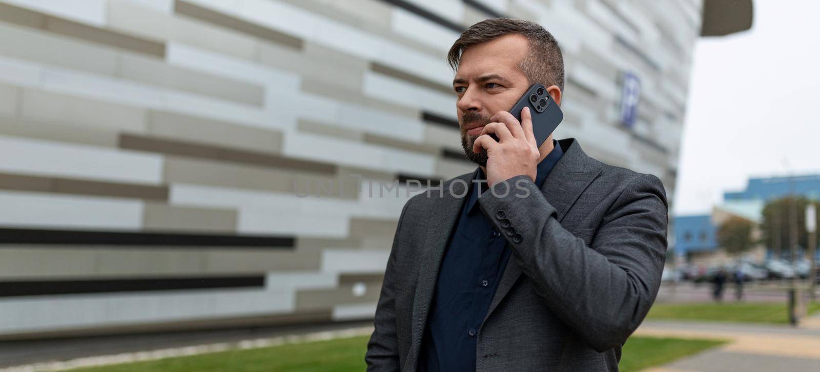 a businessman conducts a business conversation on a mobile phone against the background of a business center.