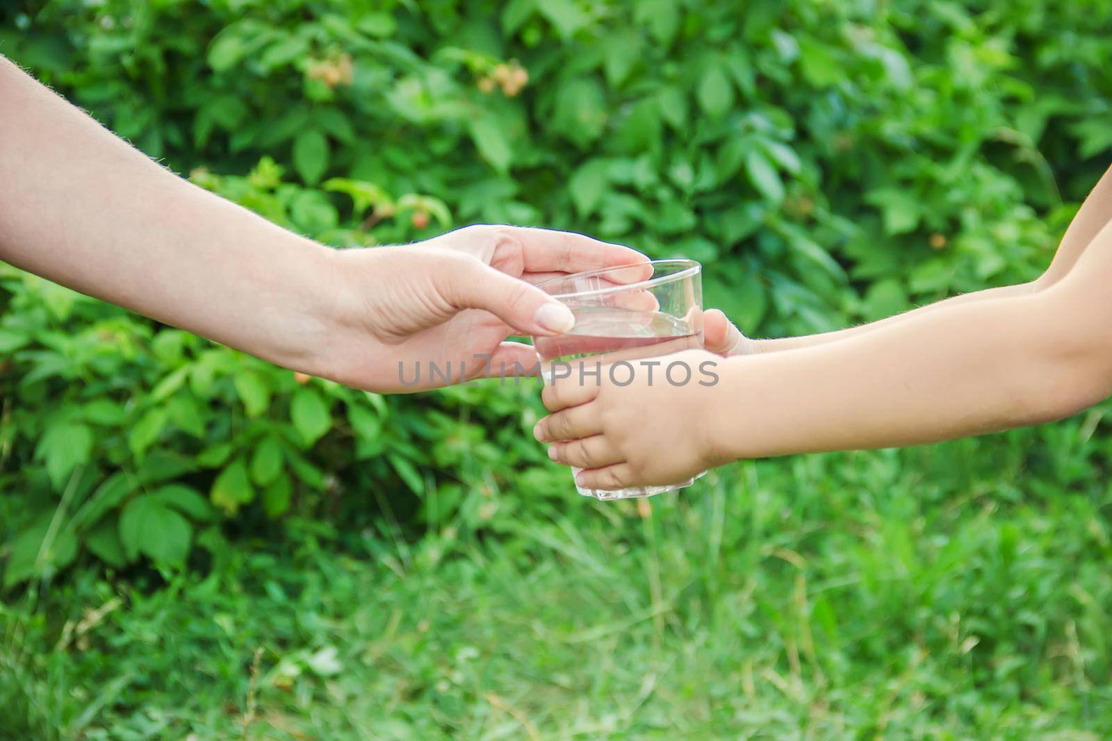 The father gives the child a glass of water. Selective focus.