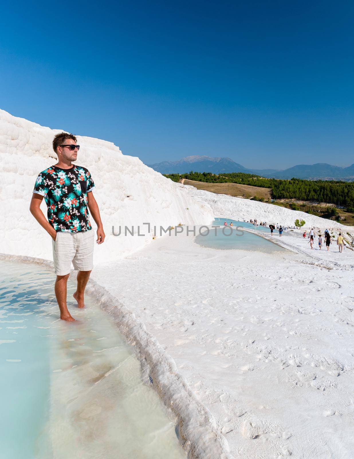 Natural travertine pools and terraces in Pamukkale. Cotton castle in southwestern Turkey,young men watching sunset at the natural pool Pamukkale Turkey