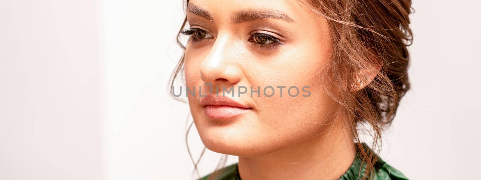 The fashionable young woman. Portrait of the beautiful female model with long hair and makeup. Beauty young caucasian woman with a brown curly hairstyle. by okskukuruza