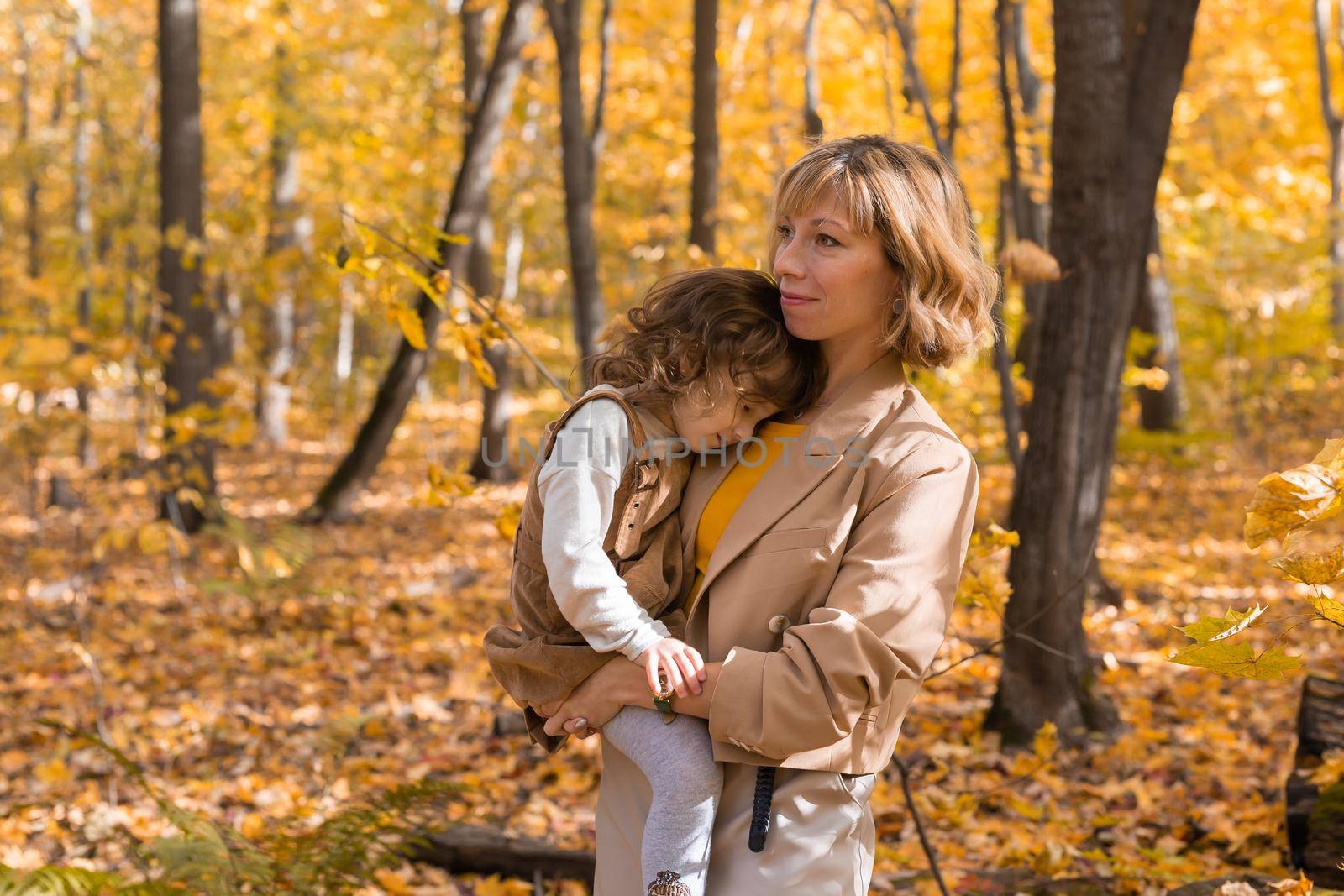 Mother with child in her arms against background of autumn nature. Family and season concept. by Satura86
