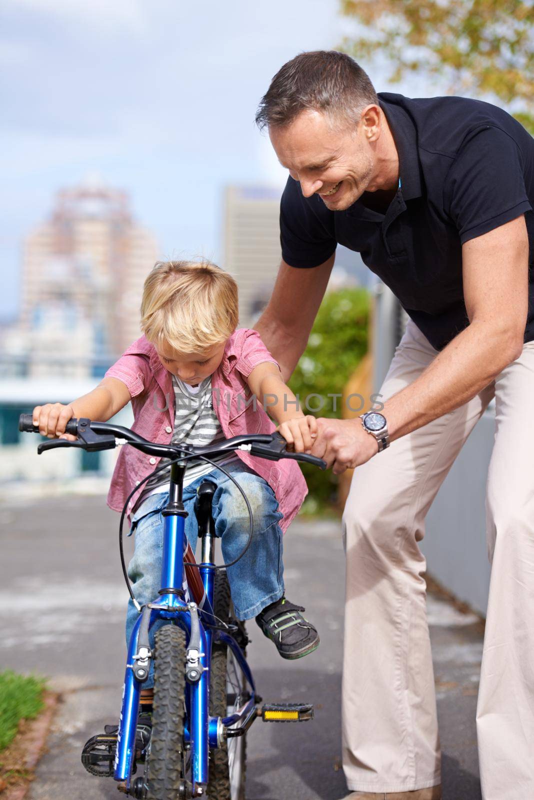His first bike ride. A father teaching his young son to ride a bike. by YuriArcurs