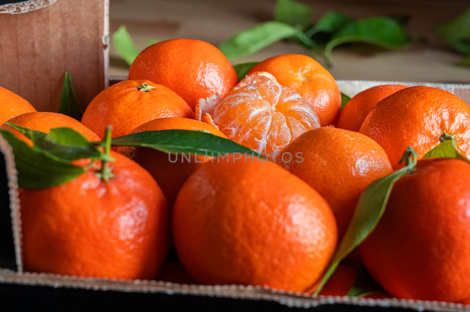 Fresh orange tangerines with leaves in a box, natural background by Annavish