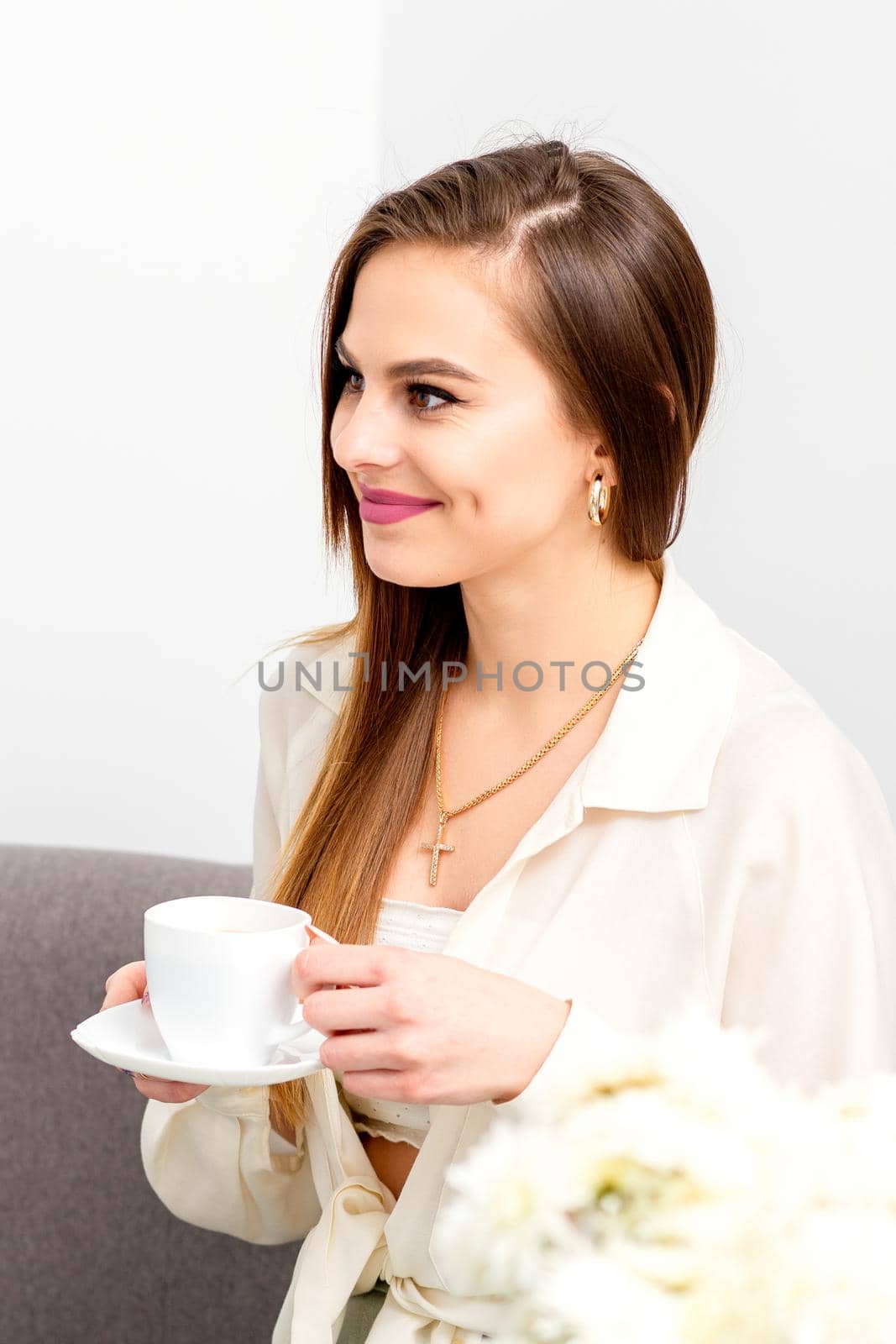 Female caucasian client with a cup of coffee in his hands smiling at a doctor's appointment. by okskukuruza