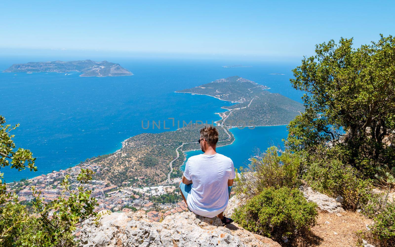 Kas turkey, Panoramic view from the mountain over the Kas Rivera, hiking up Lycian trail mountain of Kas Turkey. men looking out over ocean sitting on a rock