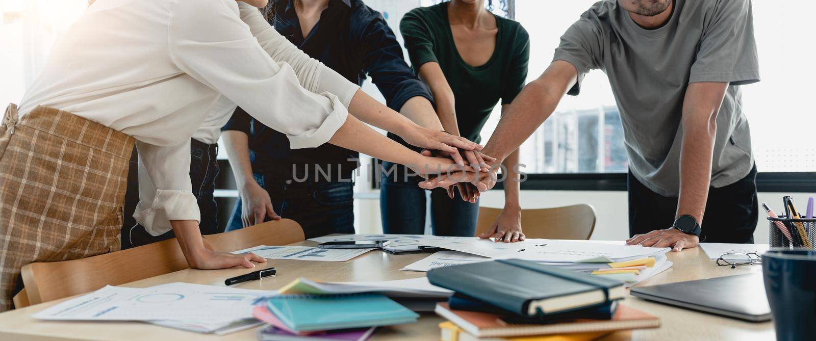 Teamwork business concept. Close up view of group of three coworkers join hand together during their meeting