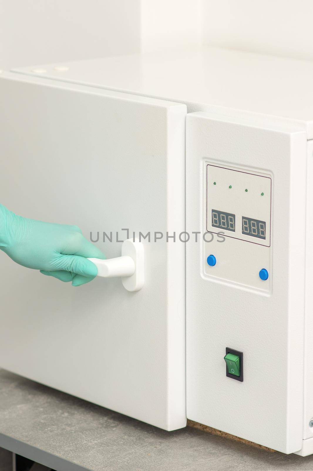 Beautician in protective gloves close the door of the machine for disinfection of tools before the medical procedures
