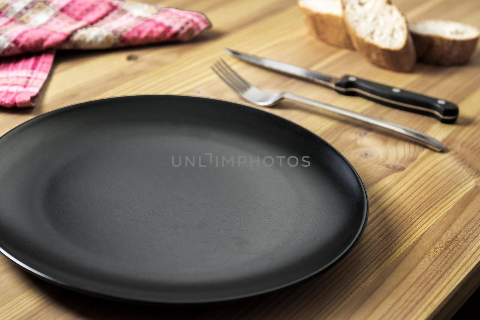 empty plate, napkin, bread, knife and fork on an aged pine wood table. Background with copy space