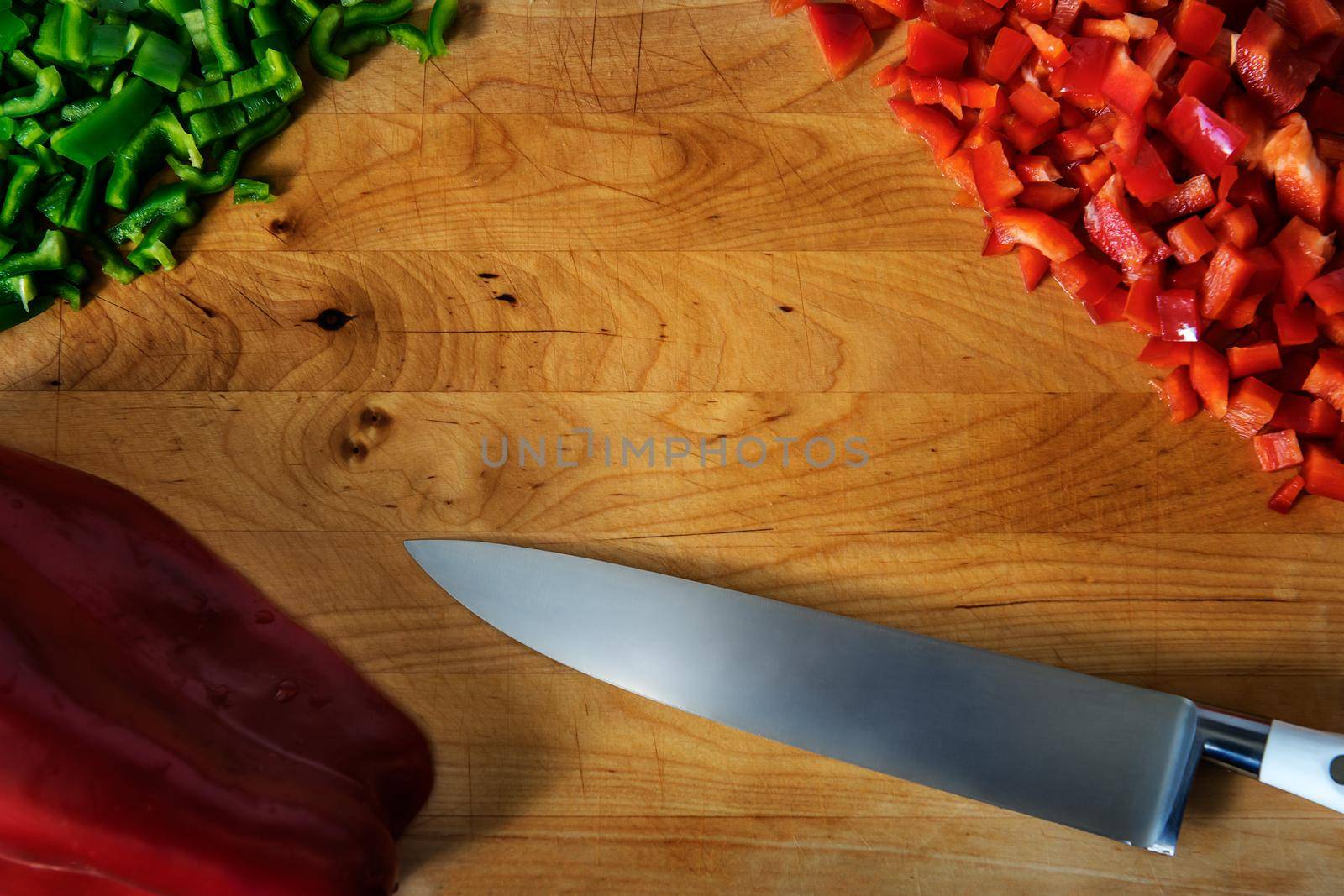 Old cutting board with a chef knife, green and red pepper chopped. Flat top view with frame style and copy space