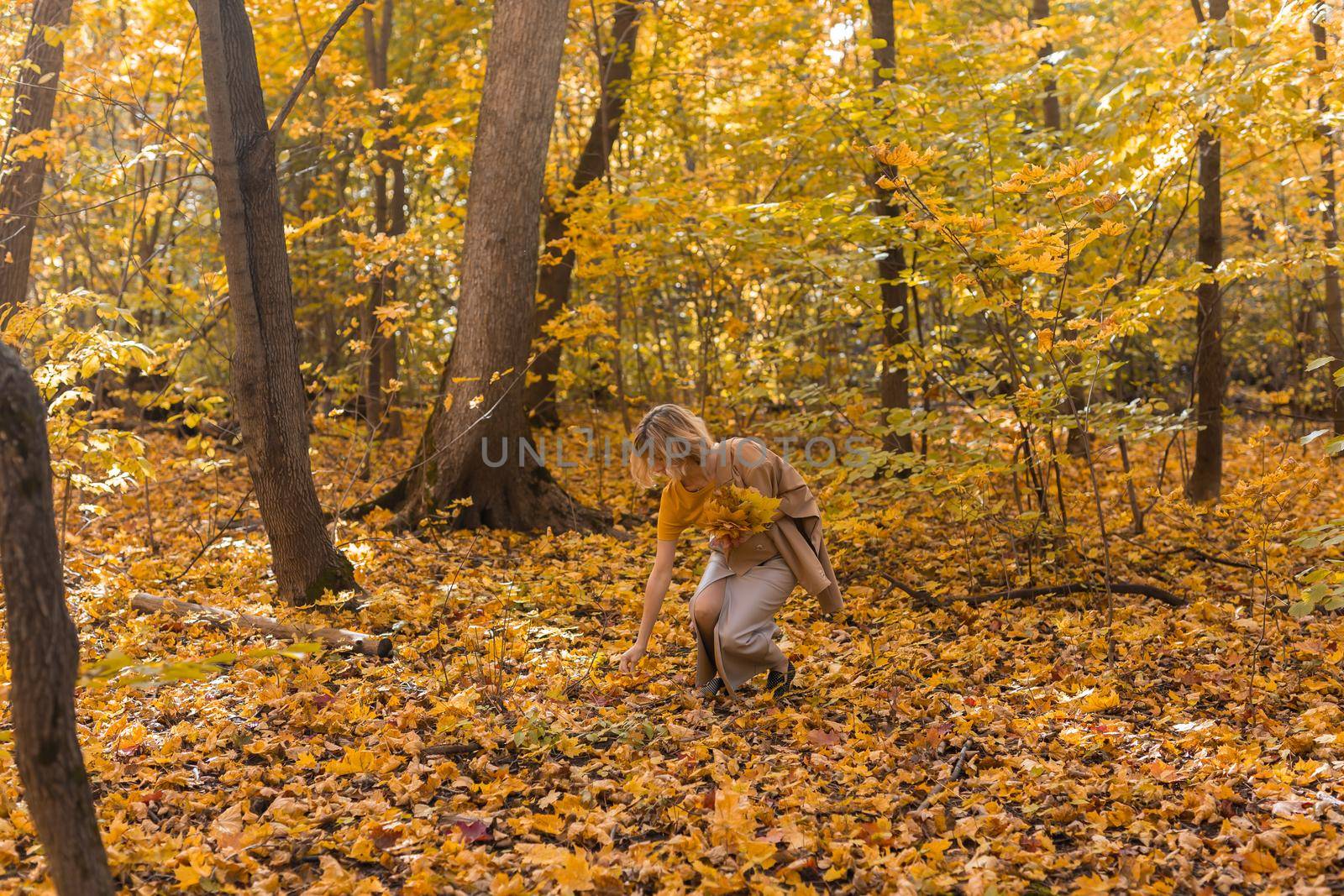 Walking woman on a fall day in the beautiful autumn park. Season and loneliness concept.