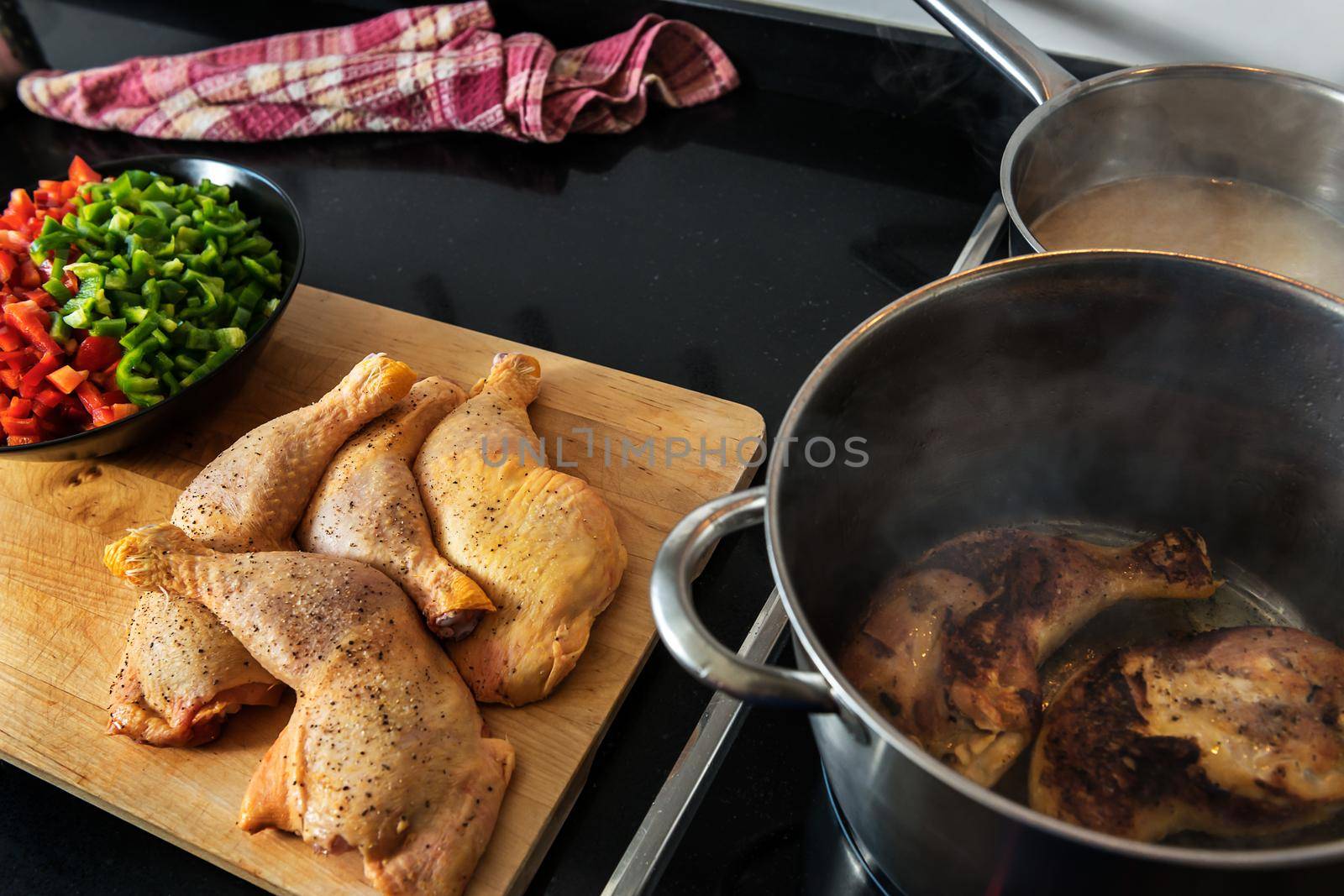 chicken fried in a pot, to cook it with the vegetables that are chopped on the plate on the wooden board, and the soup in the other pot