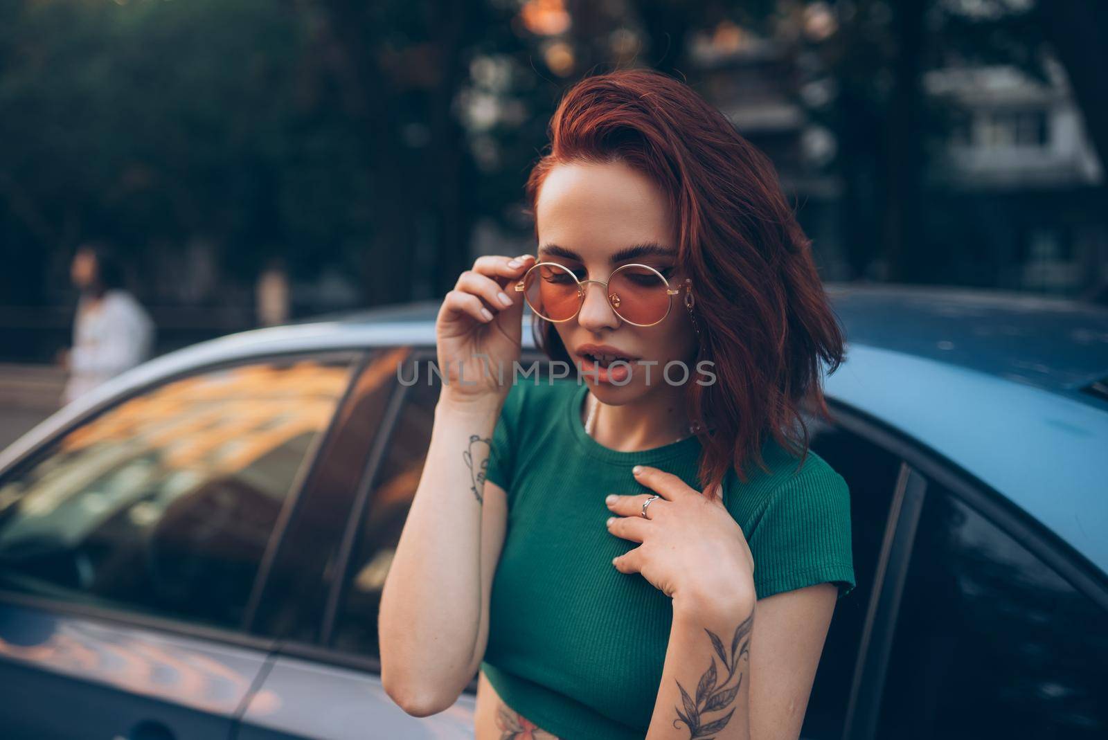 Young woman in glasses posing near car