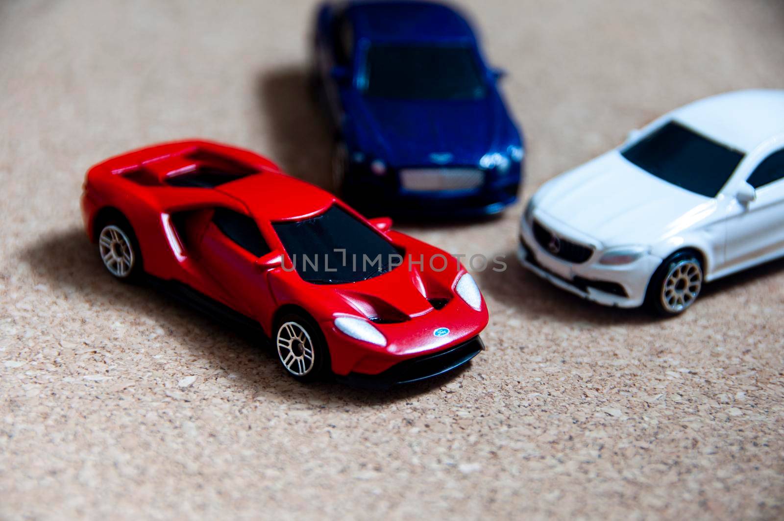 Kuala Lumpur, Malaysia - September 2022 : Selective focus of miniature toy car of Ford GT with blurred Mercedes AMG and Bentley Continental GT on wooden cover background. Copy space.