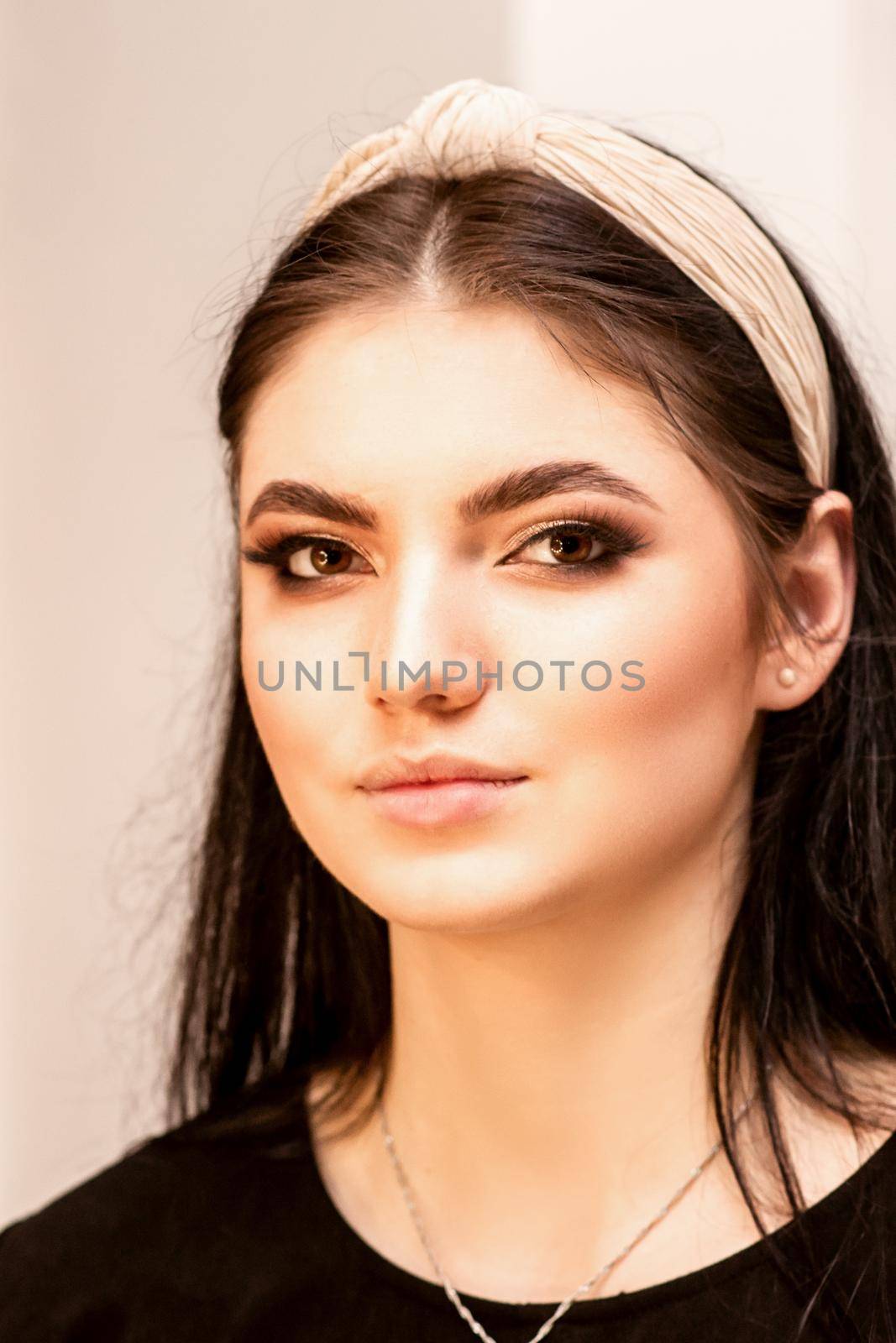 The fashionable young woman. Portrait of the beautiful female model with long hair and makeup. Beauty young caucasian woman with a hoop on her head