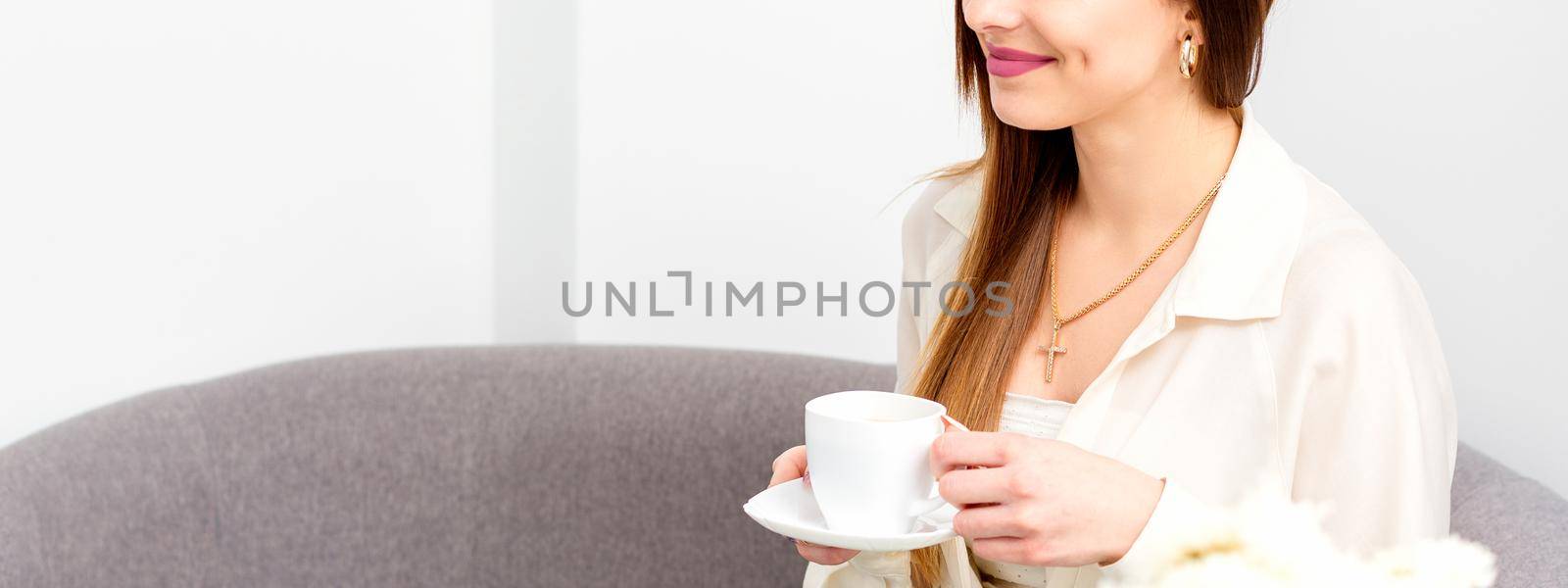 Female caucasian client with a cup of coffee in his hands smiling at a doctor's appointment