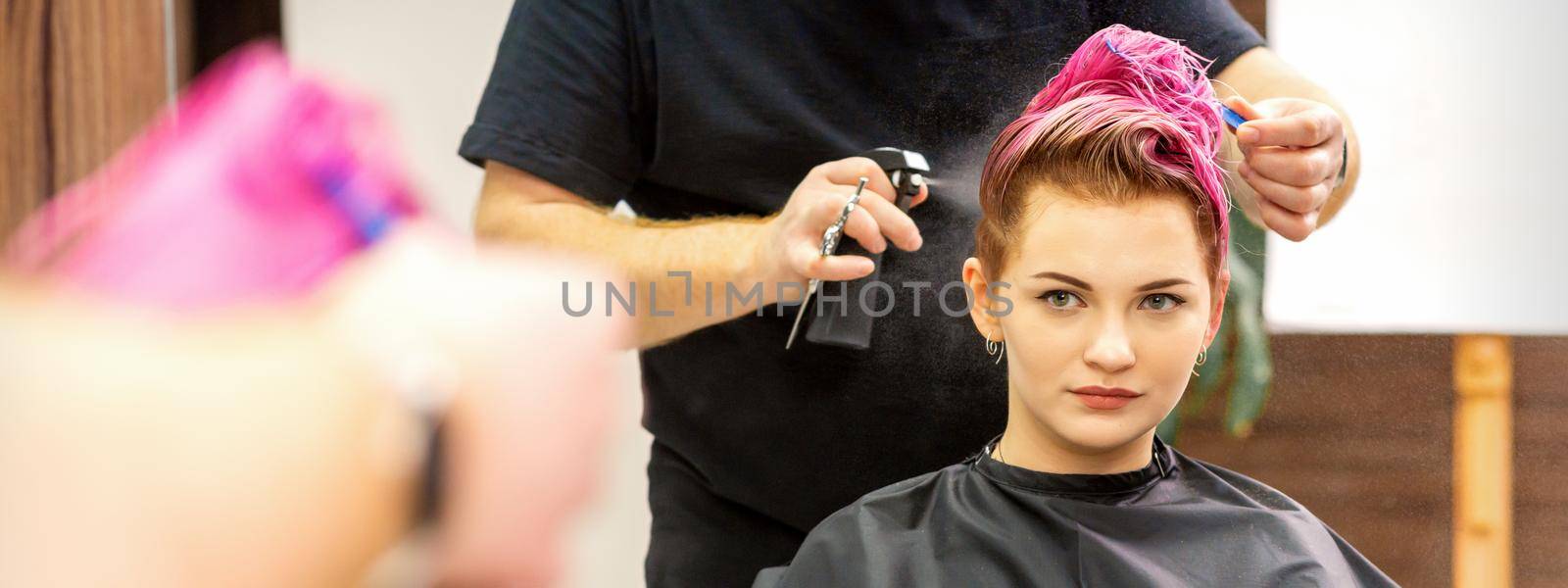 Beautiful young pink haired caucasian woman in the modern hair salon. by okskukuruza
