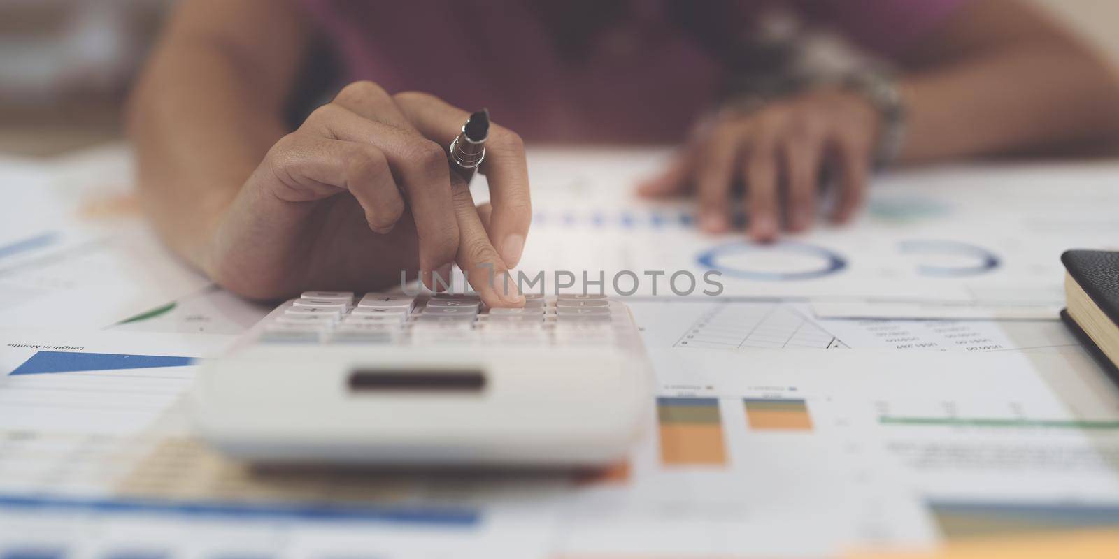 Business woman hand using calculator to calculate the company's financial results and budget. Account Audit Concept.