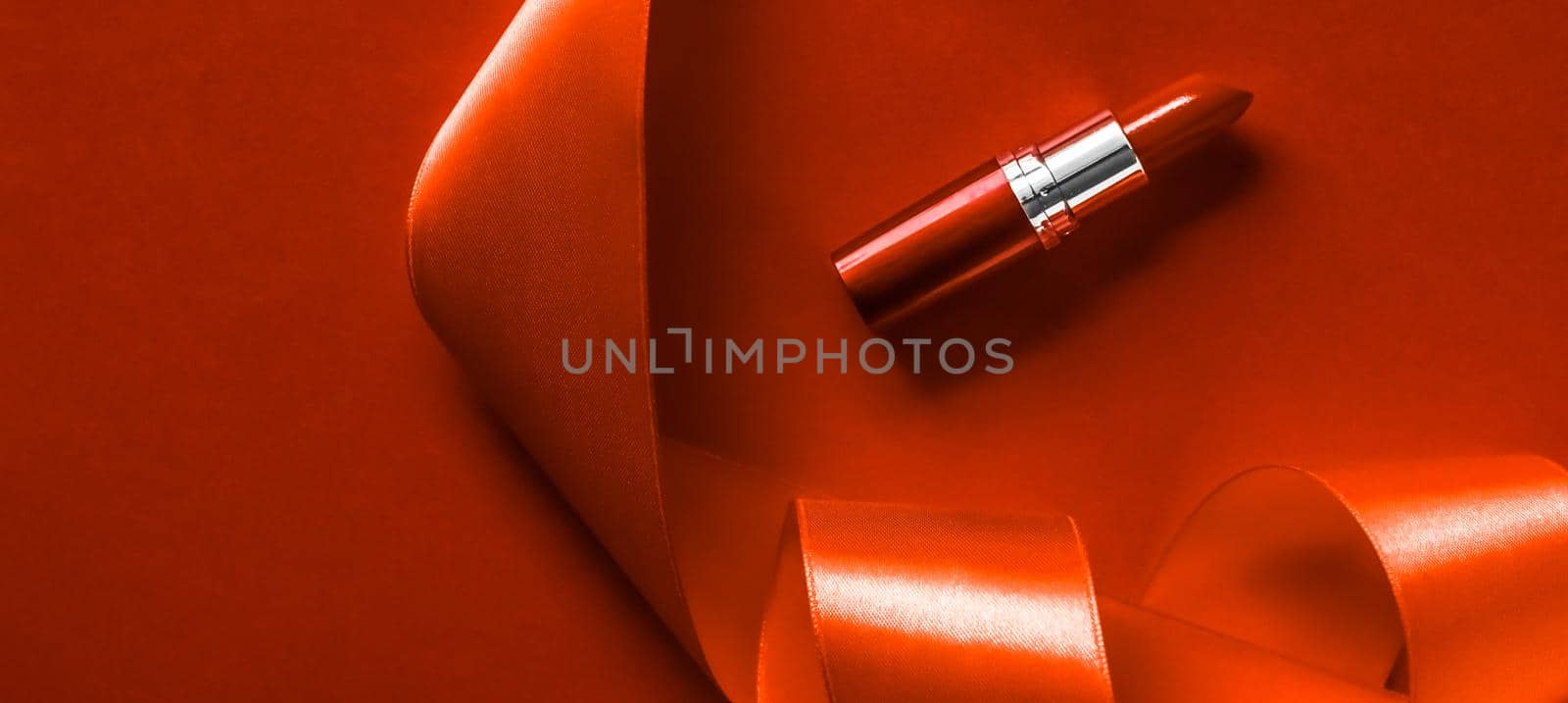 Luxury lipstick and silk ribbon on orange holiday background, make-up and cosmetics flatlay for beauty brand product design by Anneleven