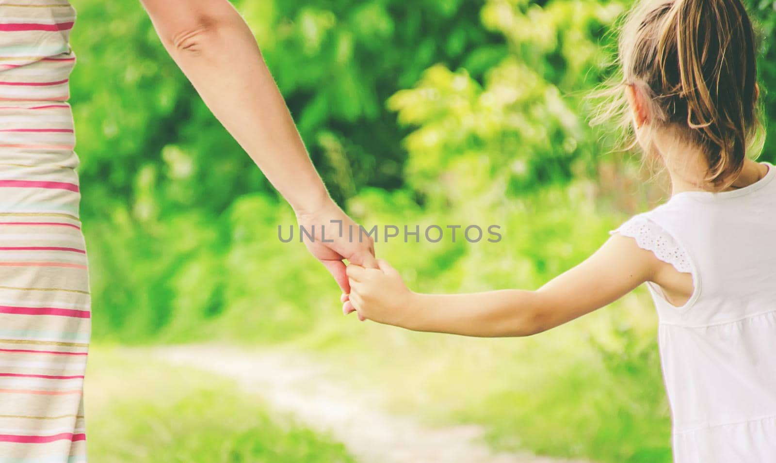 Mom and daughter are walking along the road holding hands. nature.