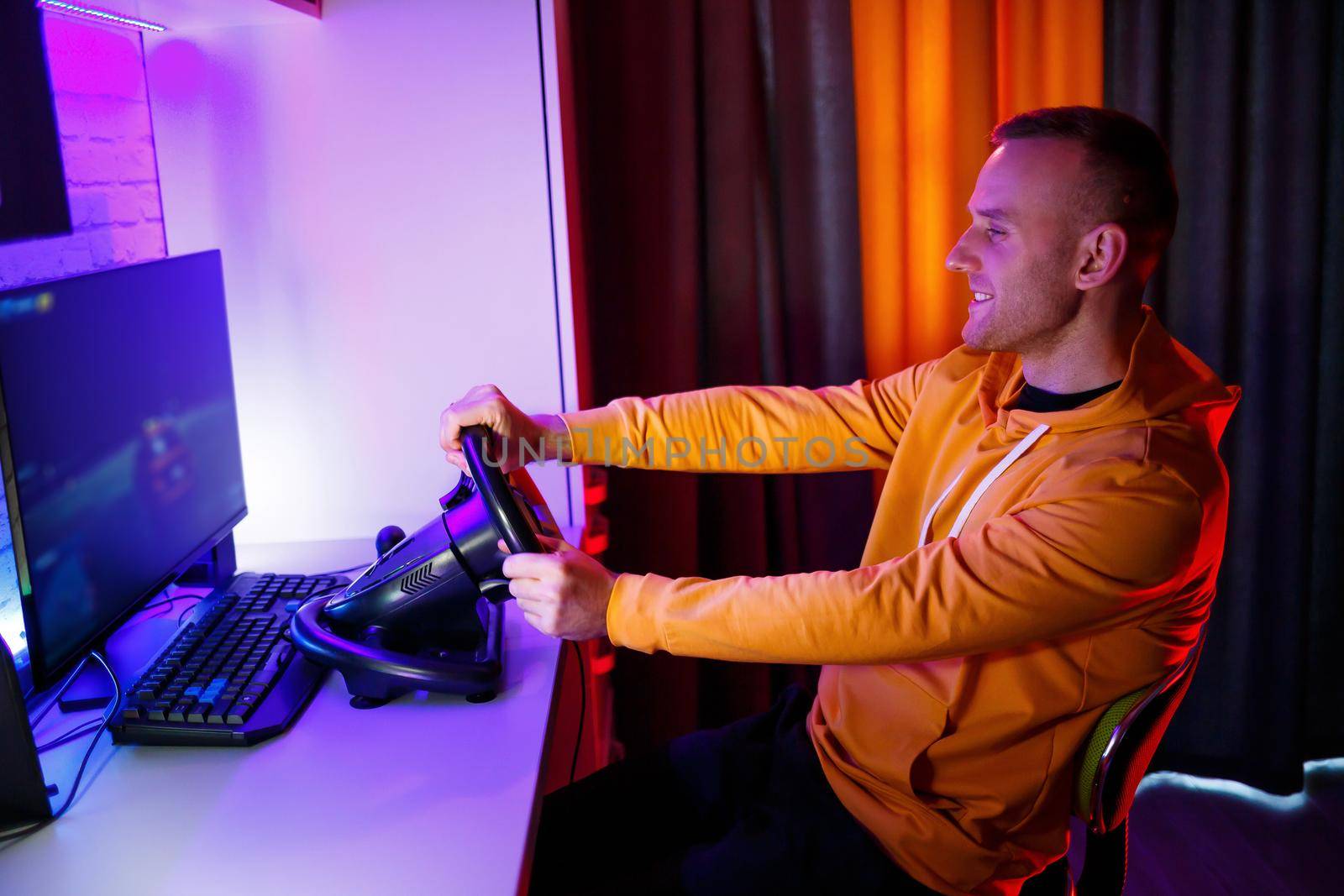 Male gamer playing racing games on the computer. He uses the steering wheel. Emotional game