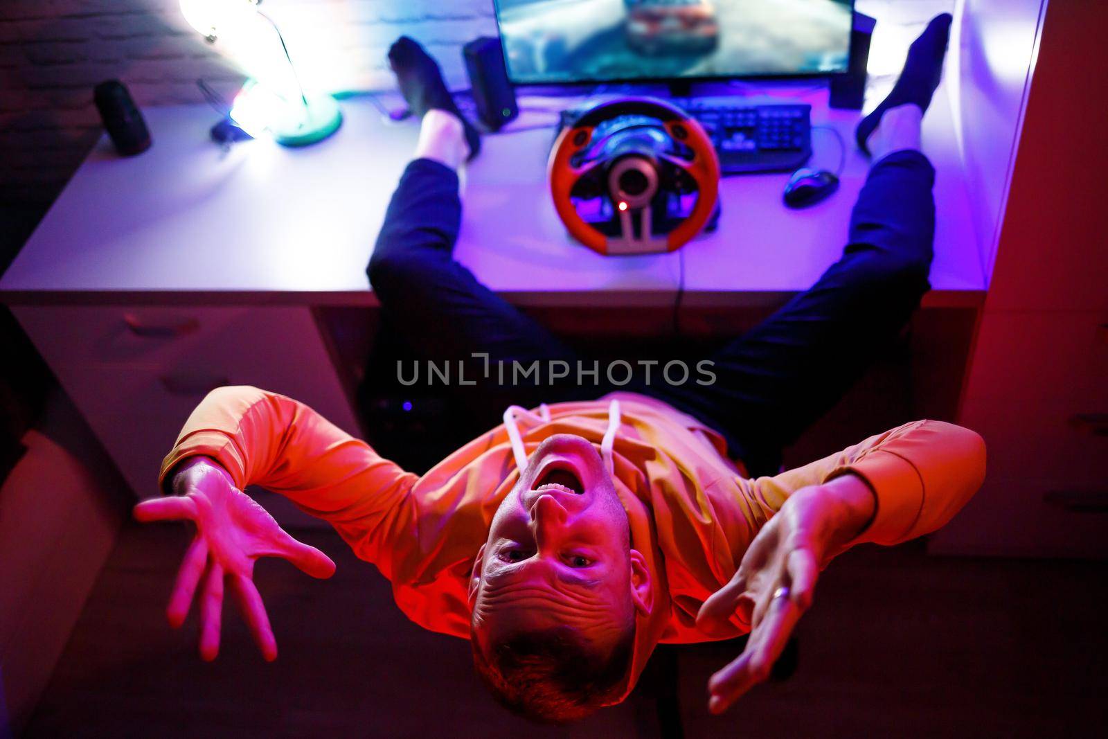 Male gamer playing racing games on the computer. He uses the steering wheel. Emotional game